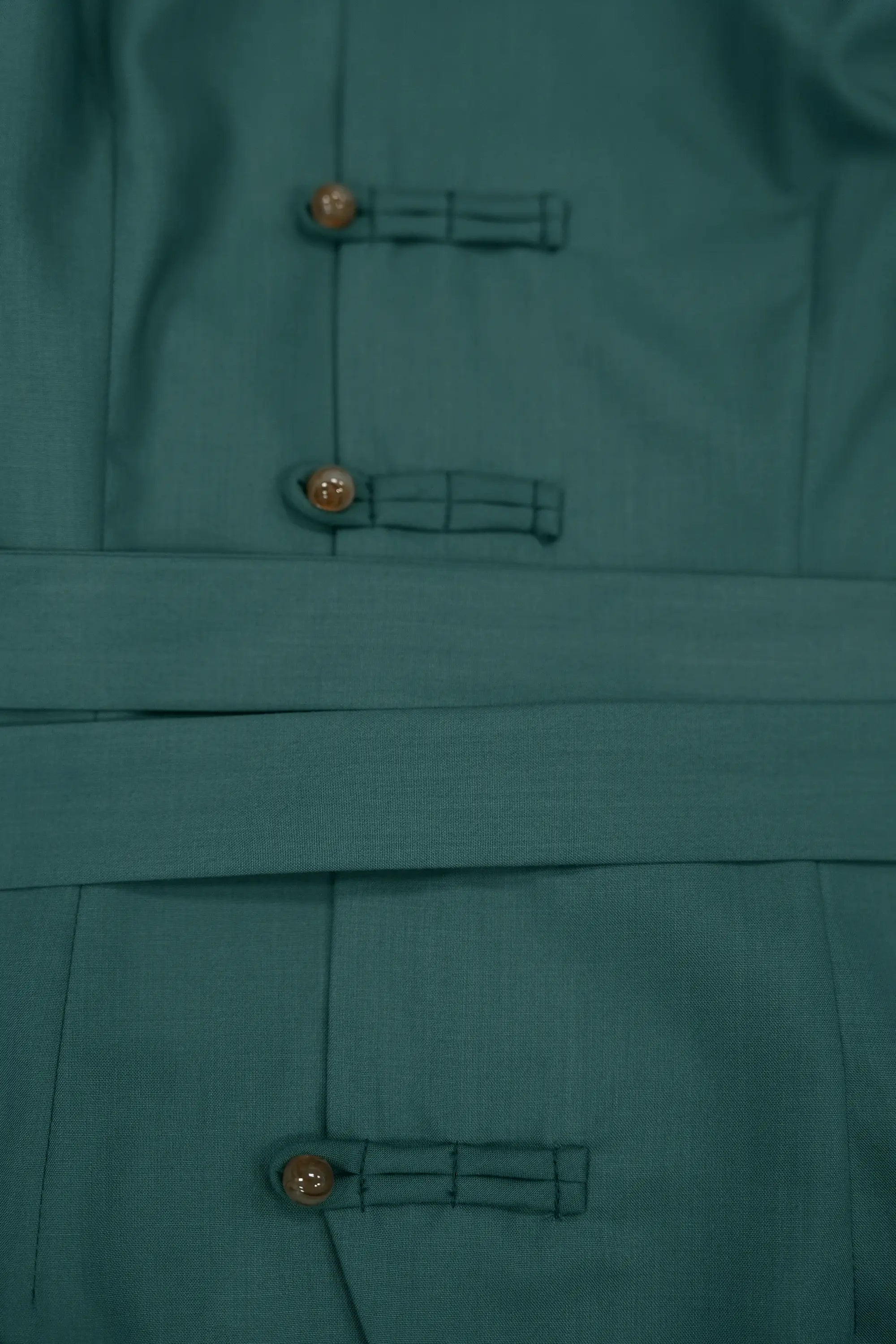 Close-up of deep green top highlighting pankou button closures and detachable waist sash, showcasing tonal detailing, clean seam lines, and refined construction across the bodice