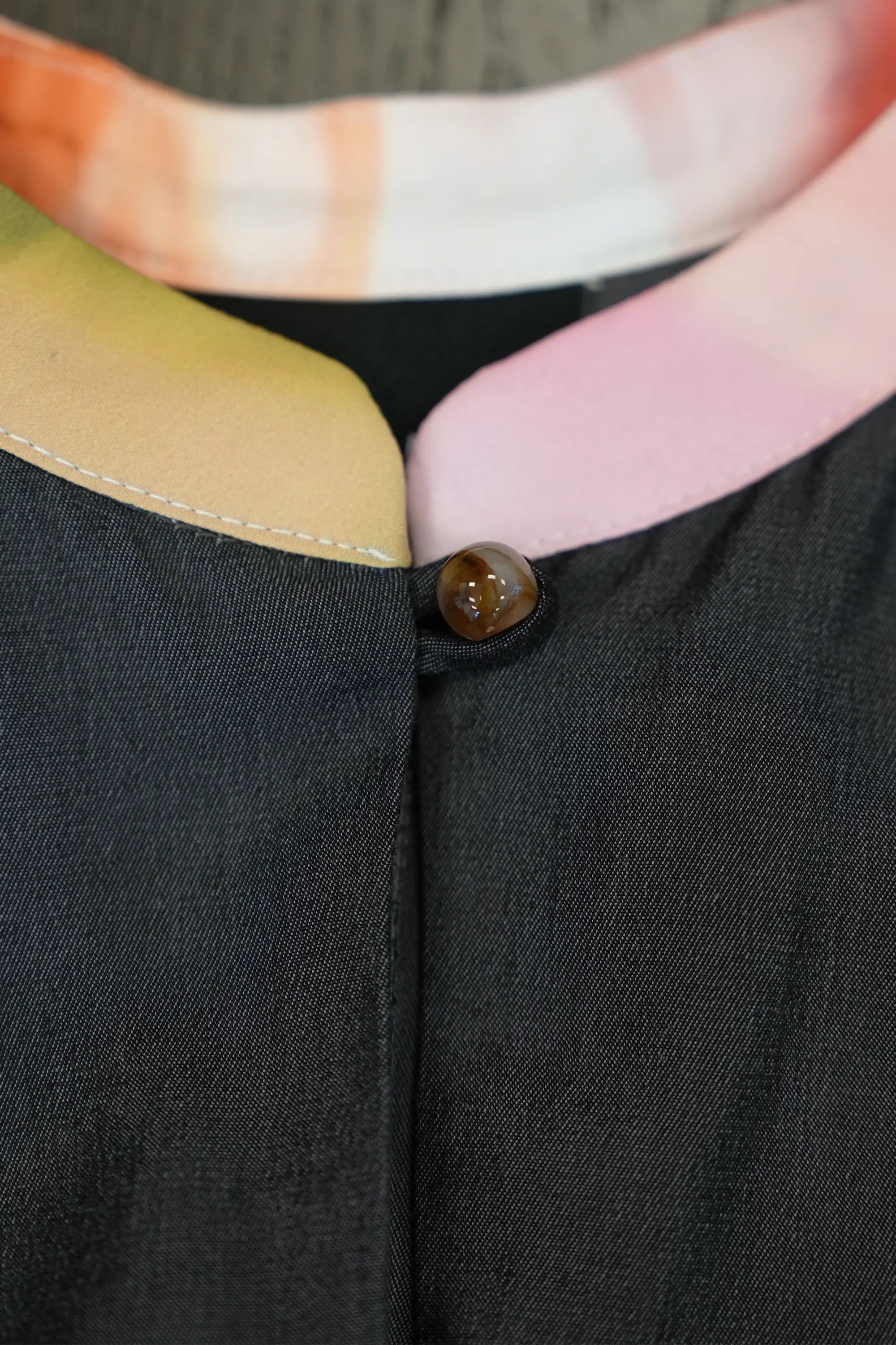 Close-up of charcoal dress featuring printed micro Chinese collar neckline with soft contrast panels, highlighting the polished button fastening, clean seam construction, and smooth, lightweight fabric texture