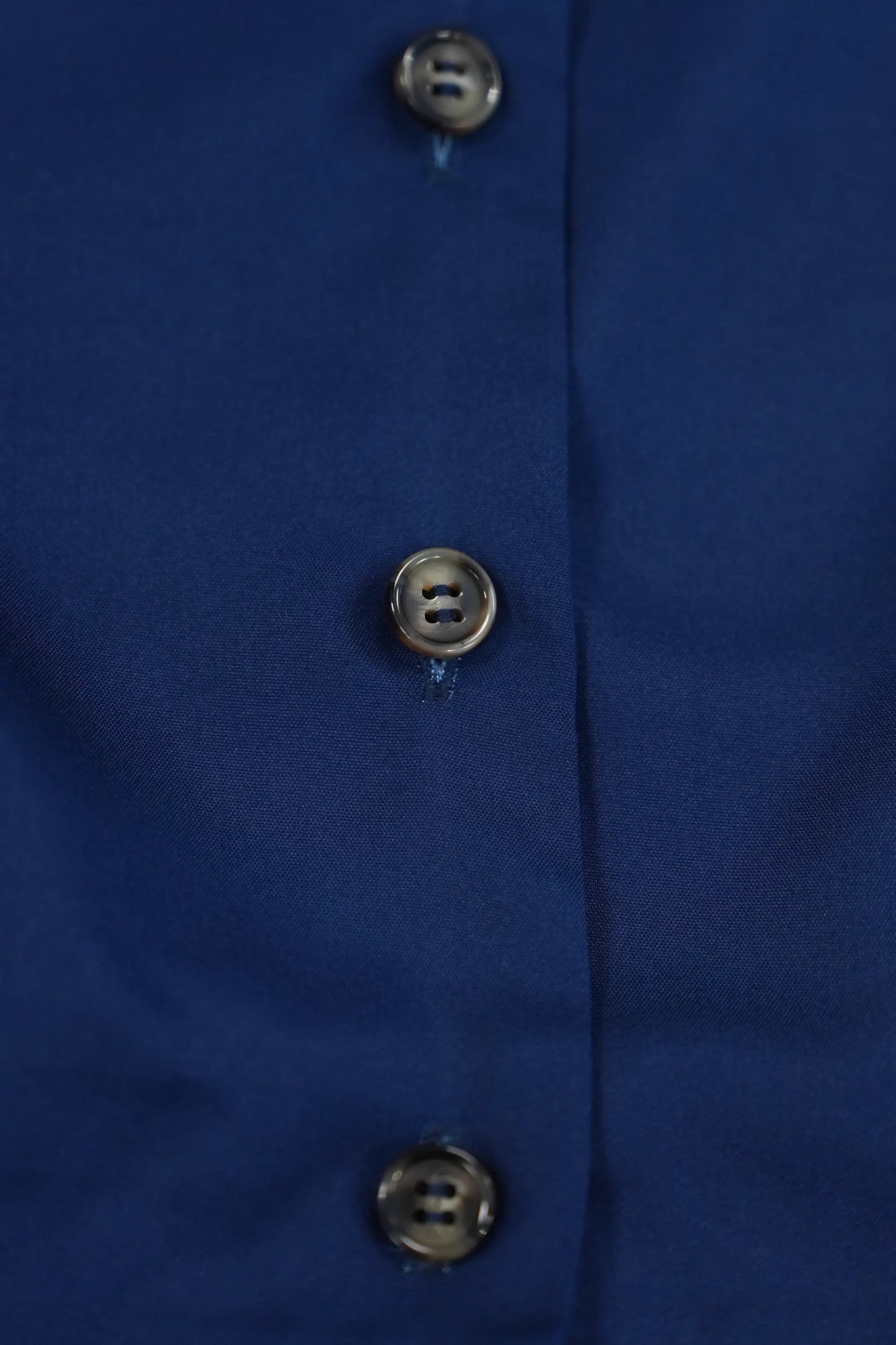Close-up of button-down front on navy fabric, featuring polished buttons and clean placket construction for a refined finish