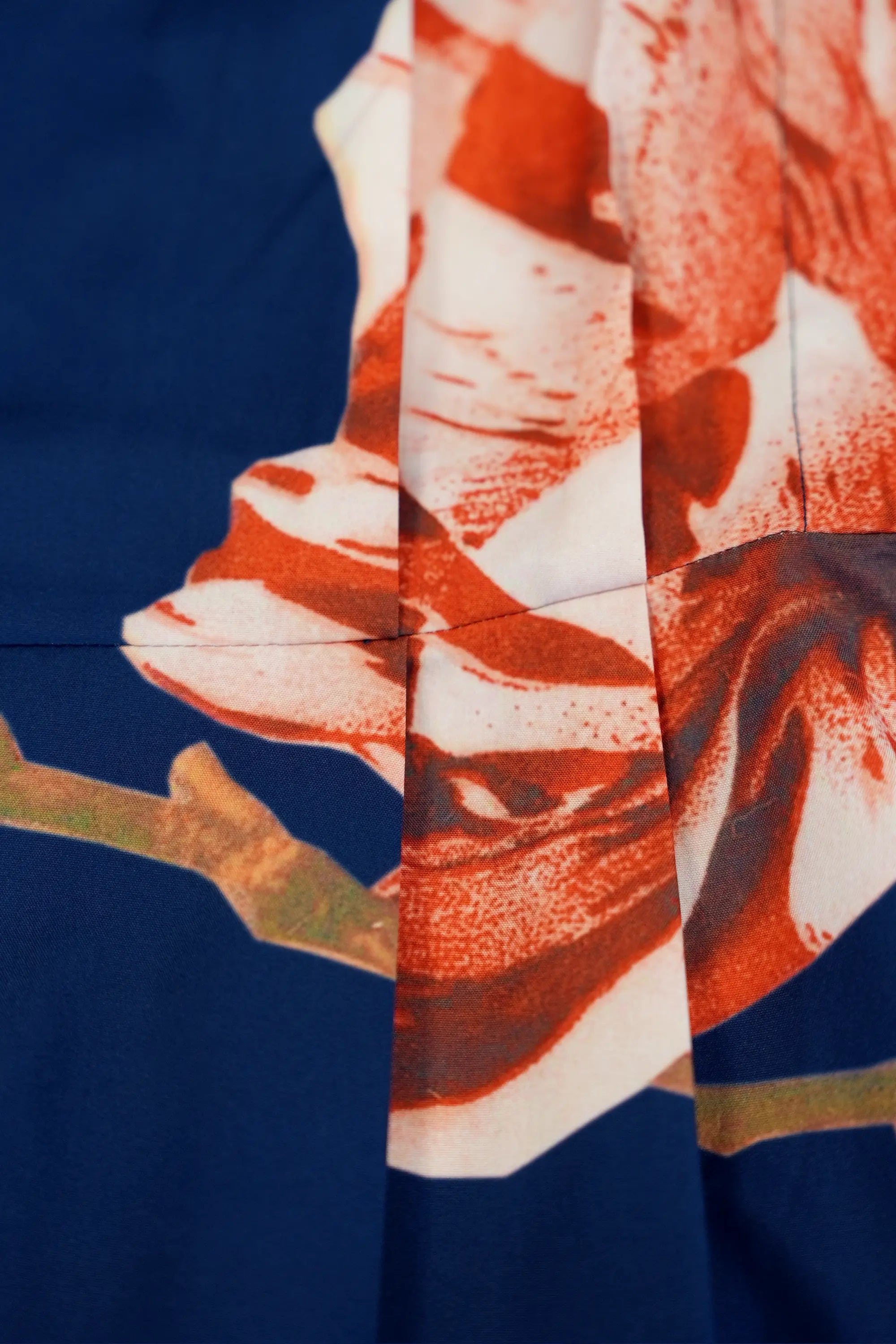 Close-up of floral print panel on navy fabric, showcasing vivid red and ivory botanical motifs with precise seam alignment and clean construction details