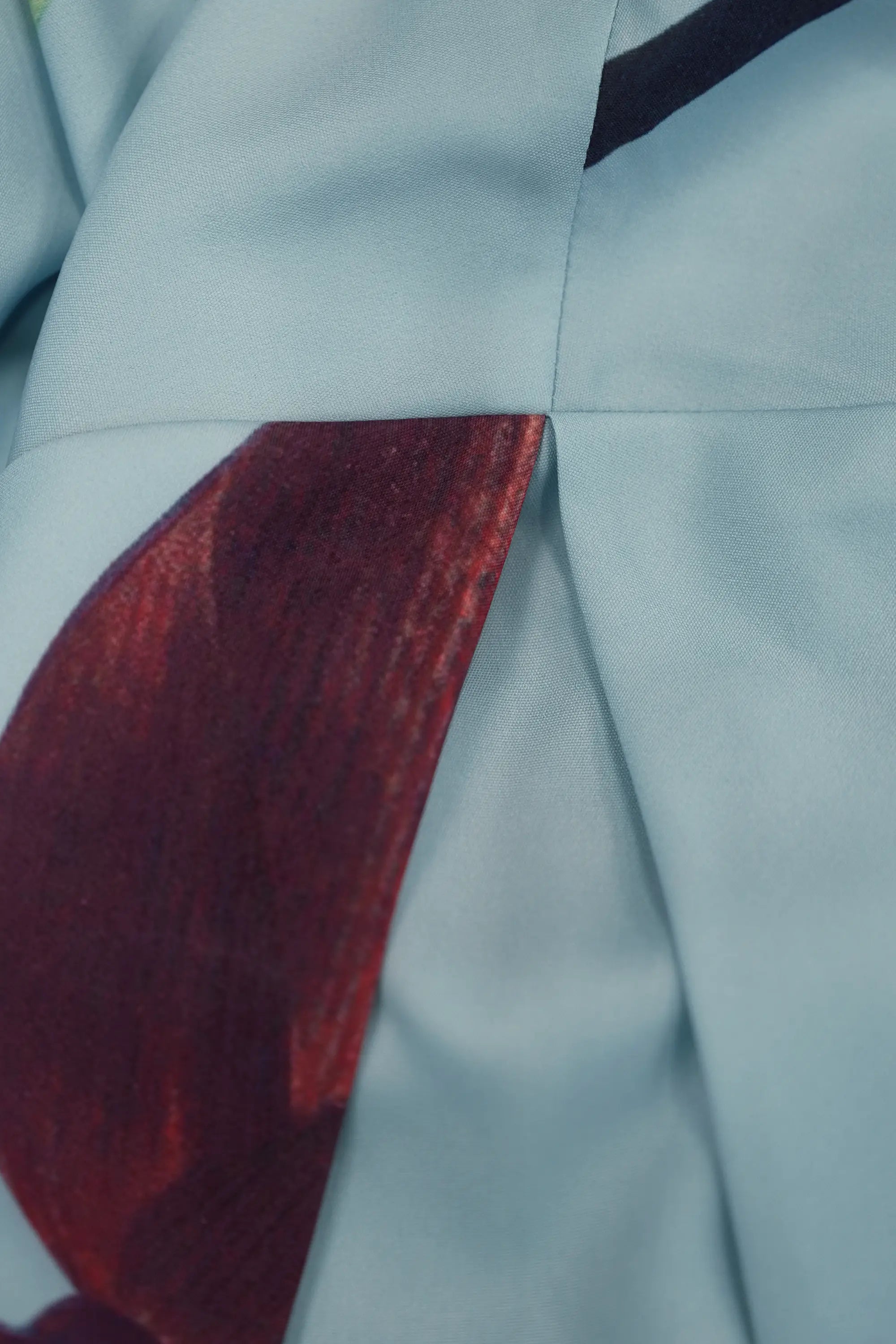 ABIDE placement print mini dress pleat detail with contrast panel seam in light blue (close-up)