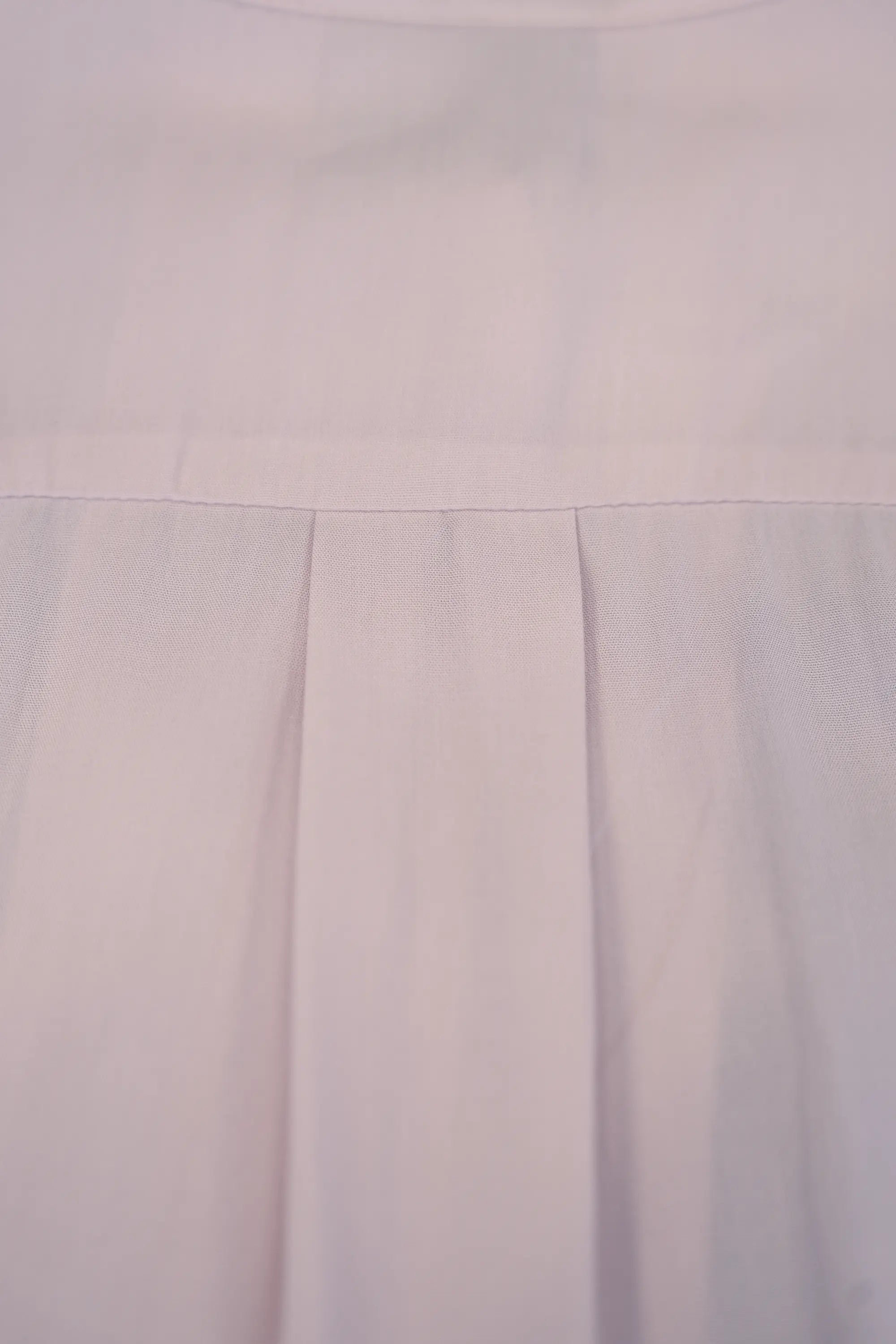 Close-up of blush pink blouse showing button-front placket with tonal buttons and smooth fabric texture