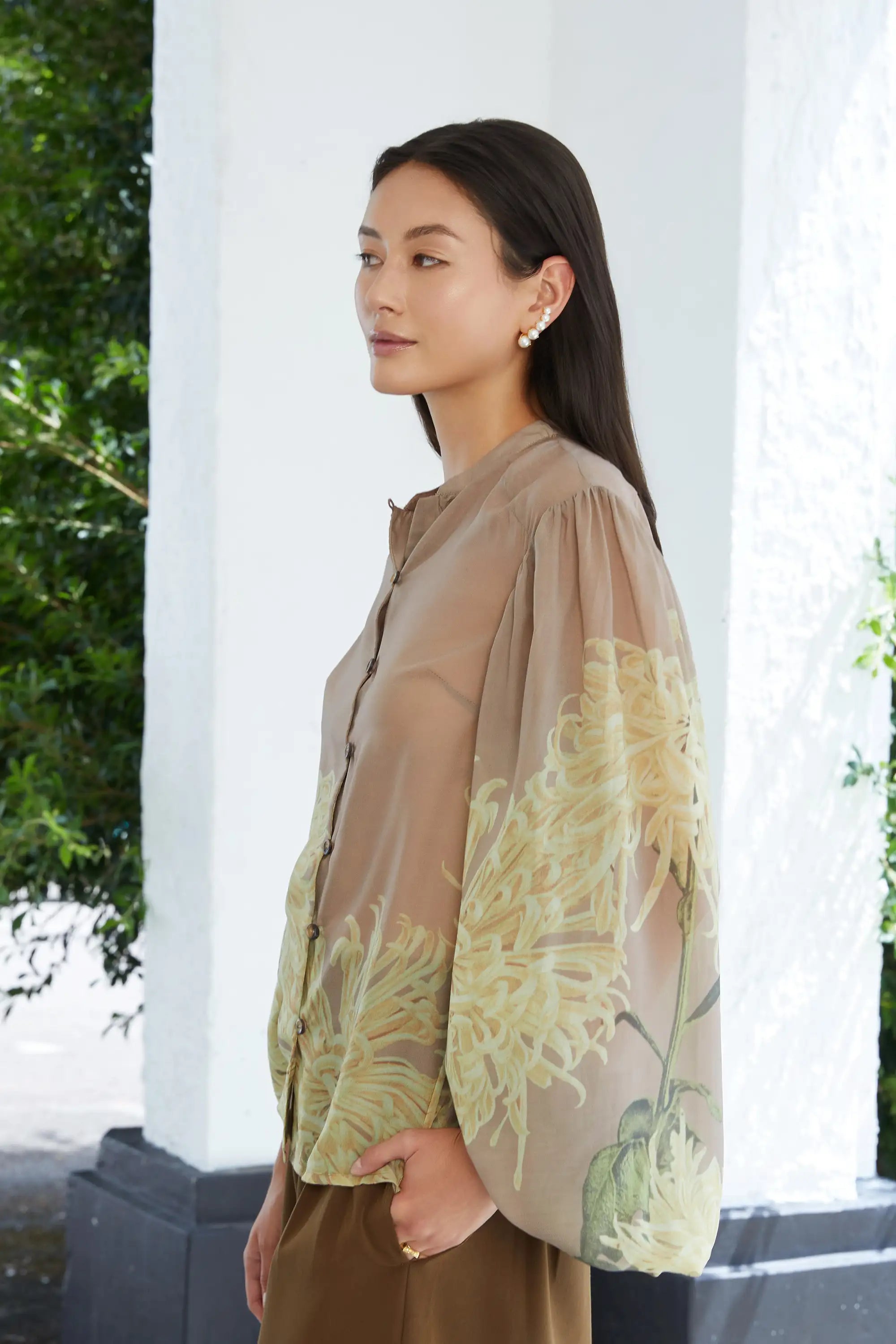 Woman wearing ABIDE sheer floral blouse with voluminous sleeves (side view)