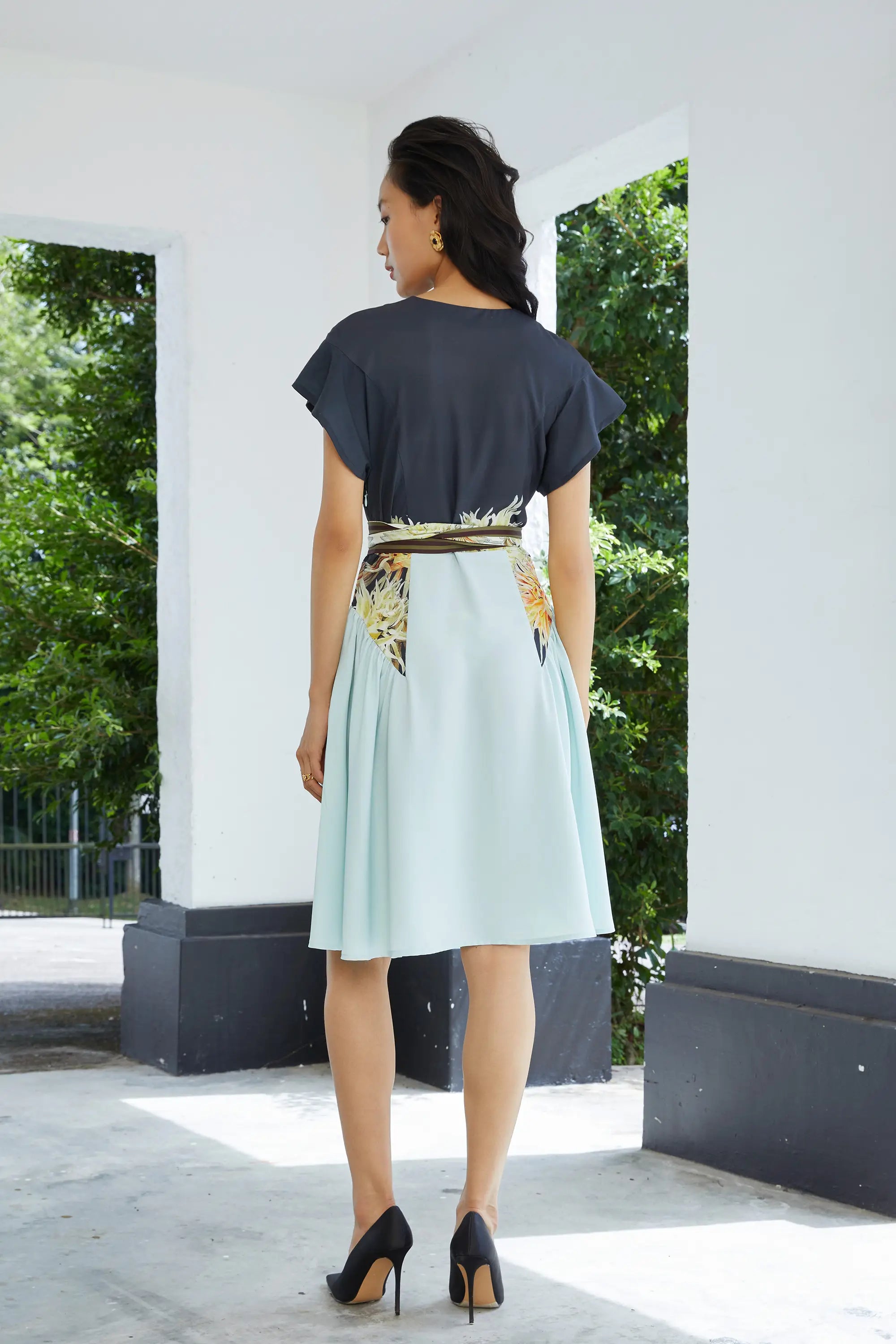 Woman wearing ABIDE contrast panel midi dress with sash belt and soft drape (back view)