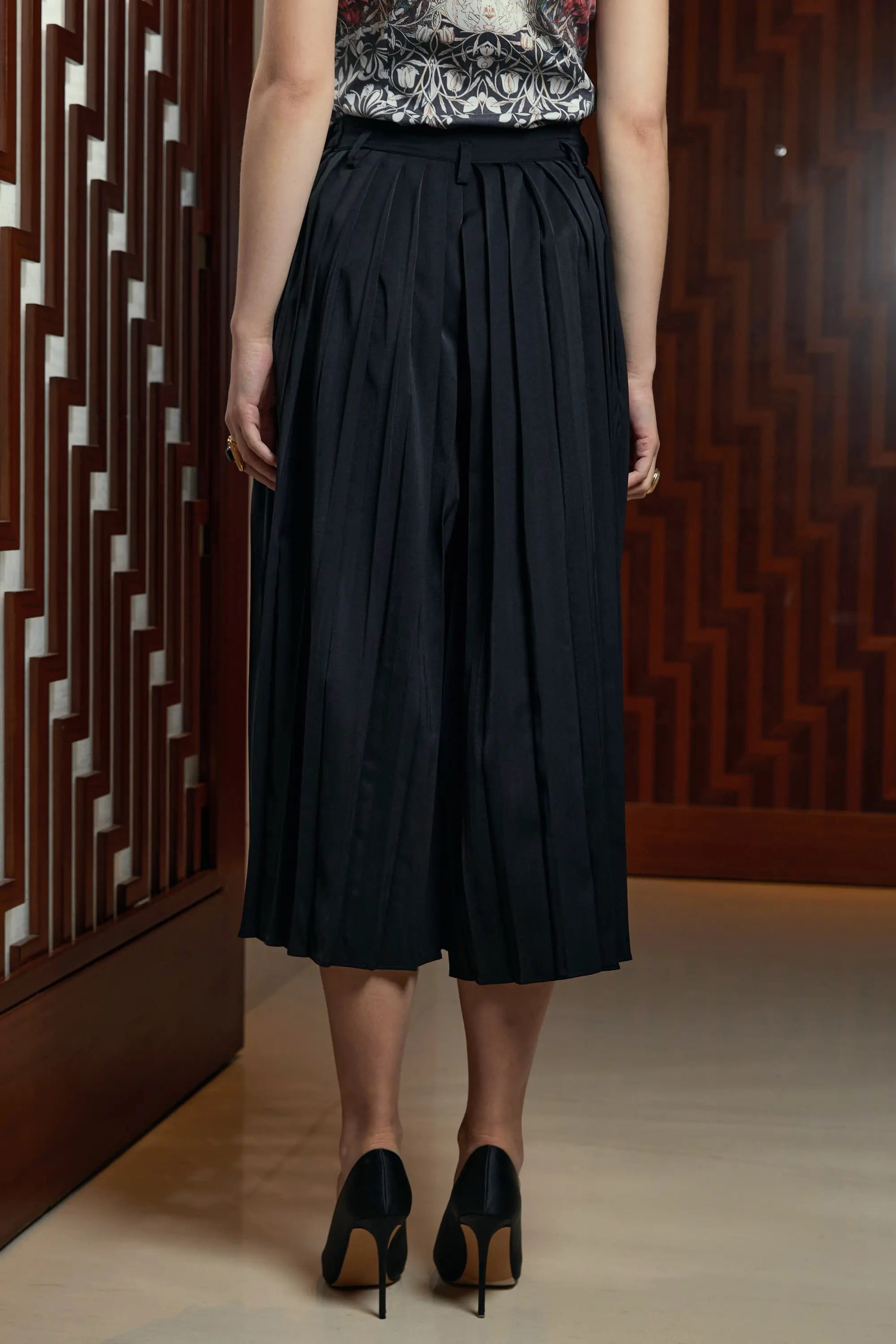 Woman wearing Arrayed black pleated skirt trousers, back view
