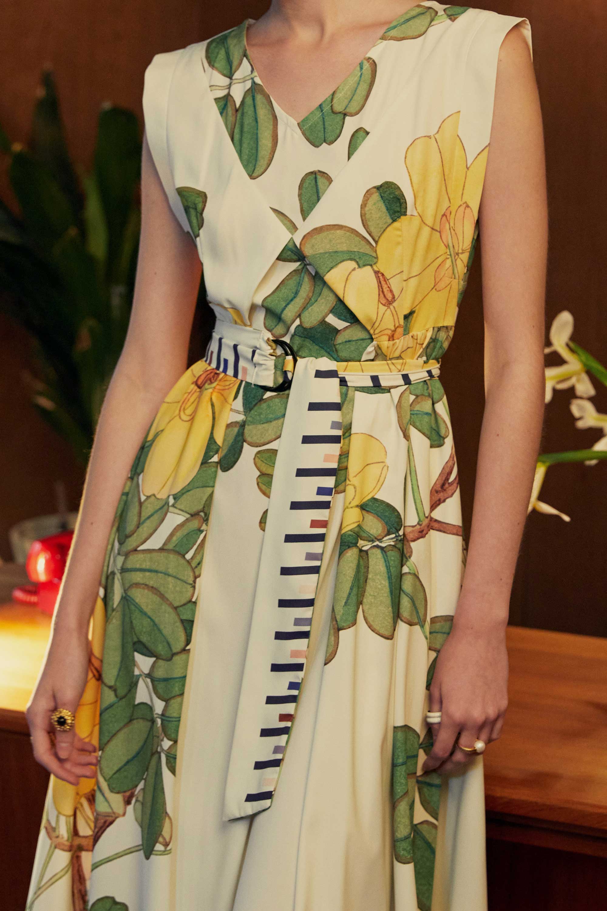 Close-up of BEHOLD Origami Square Sleeve Dress in Allamanda print, showcasing V-neckline, square sleeve cut, and striped waist sash with yellow floral motifs.