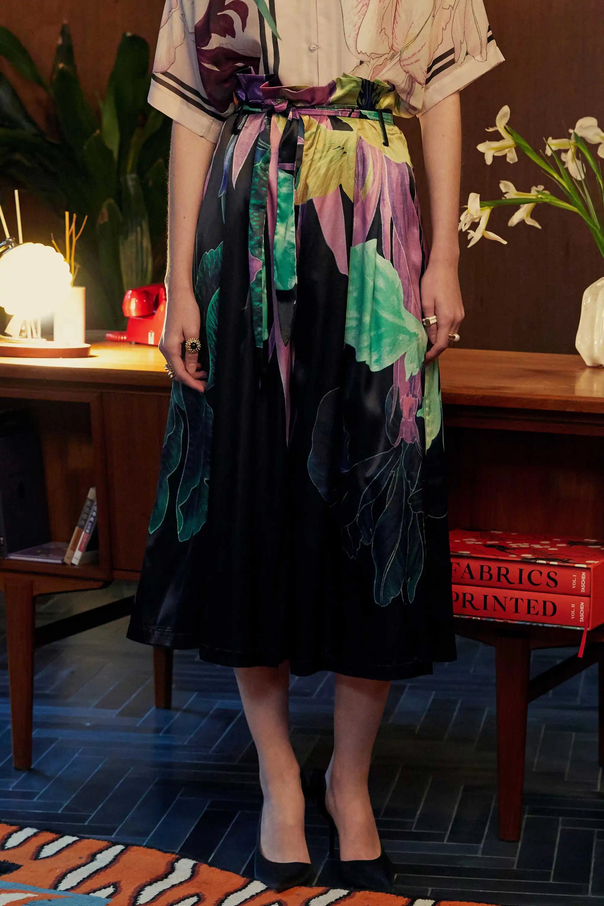 BEHOLD Iris Floral Paperbag Palazzo Pants by Reckless Ericka – close-up front view of high-waisted wide-leg pants with sash belt, styled indoors with warm lighting.