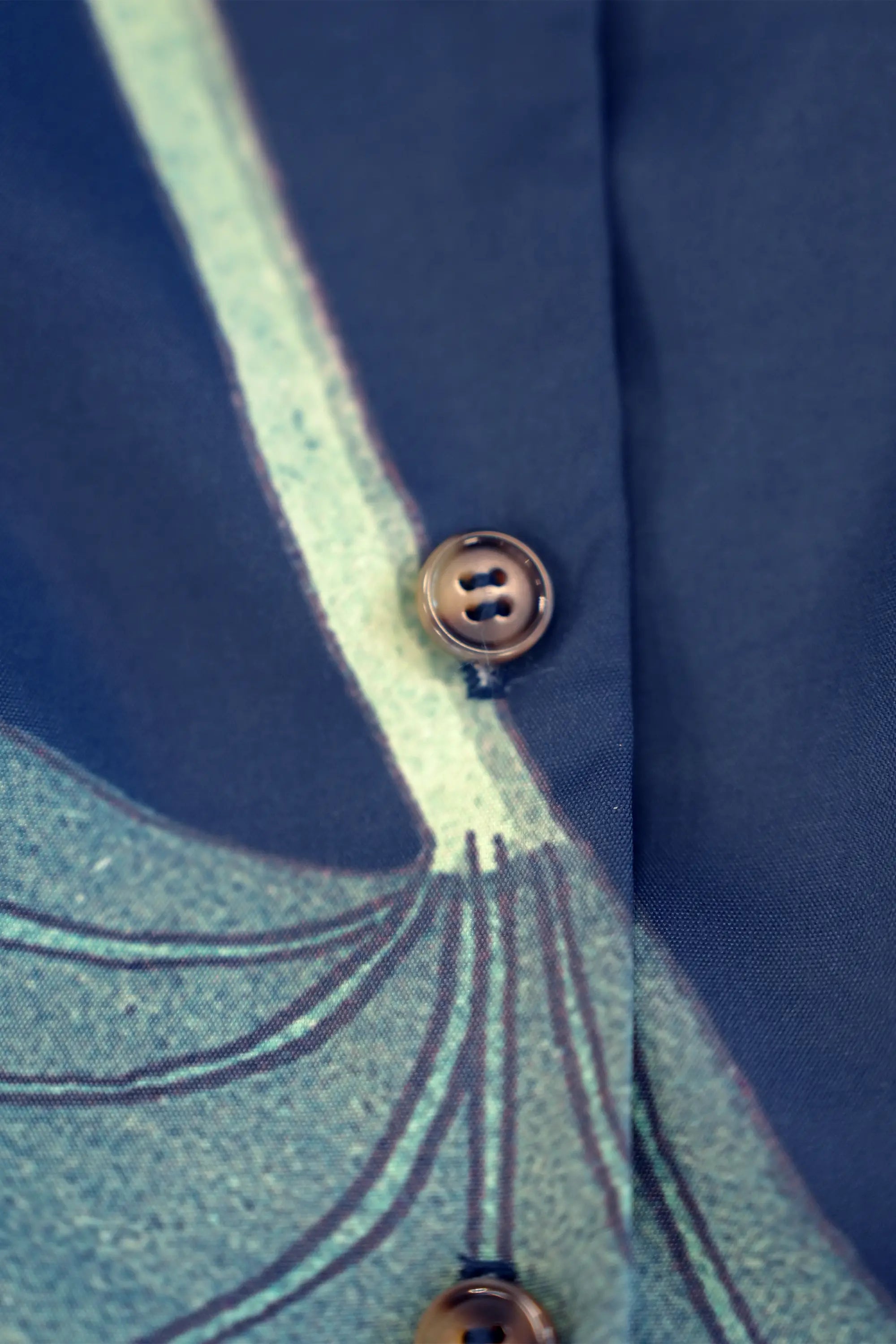Close-up of button fastening on navy dress, highlighting construction and print alignment