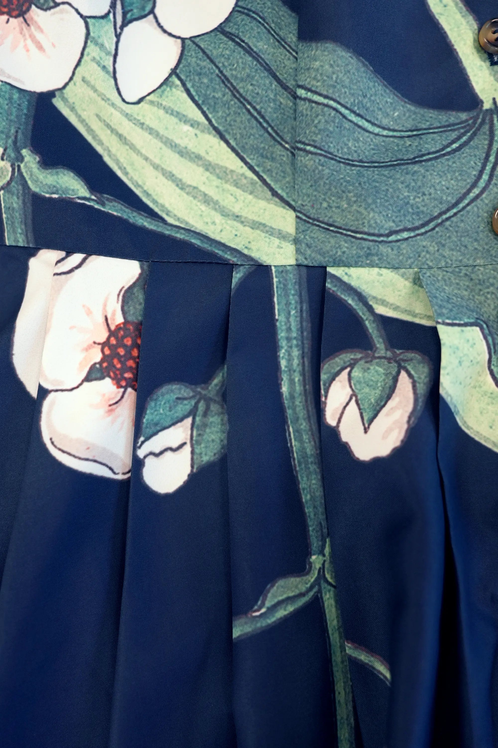 Close-up of skirt pleats with botanical print, highlighting volume and fabric drape