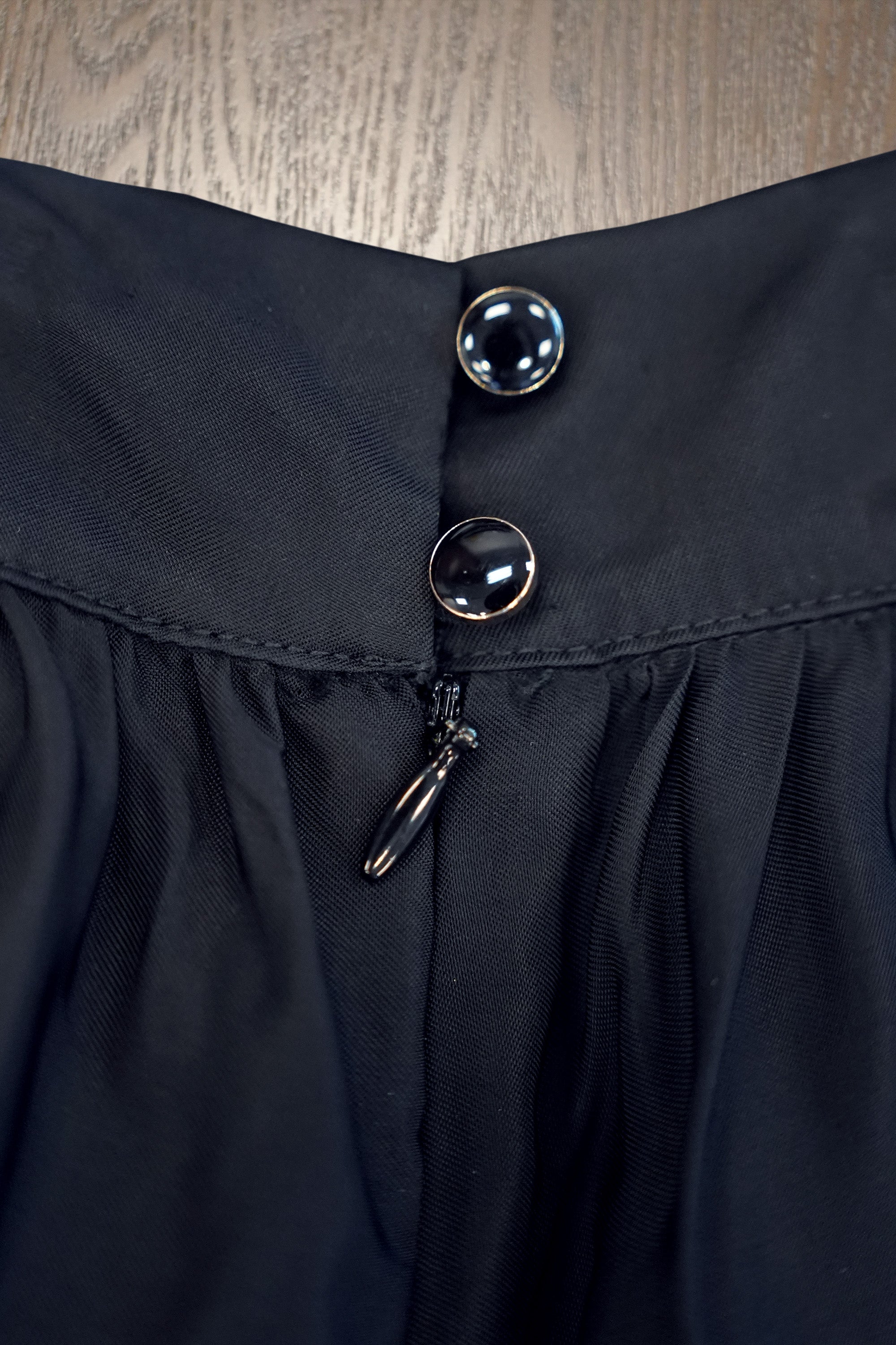 Close-up of billowing skirt featuring side button fastening with concealed zip and clean finishing at the waistband