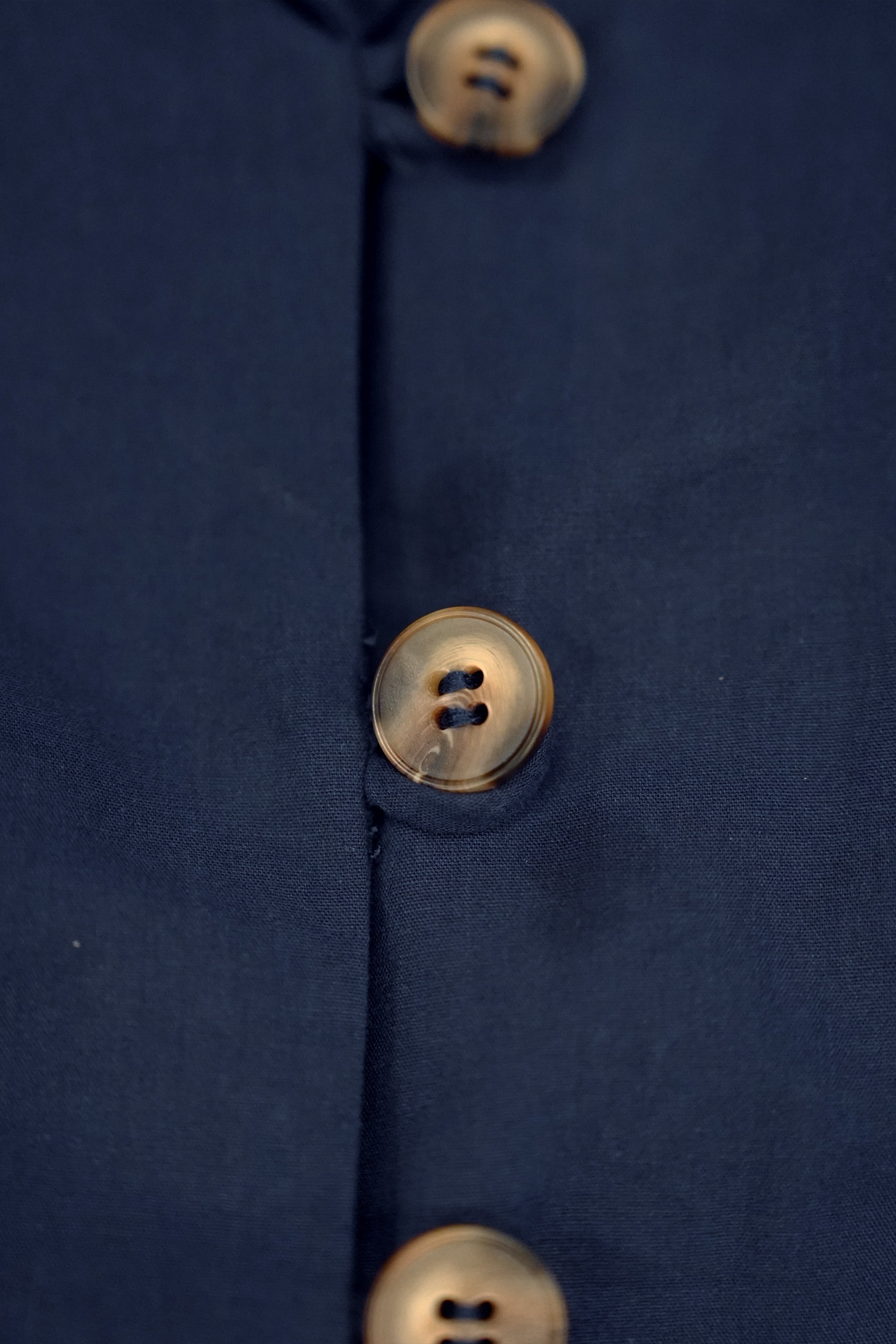 Close-up of button detail on navy cropped top, featuring tonal buttons and clean finishing