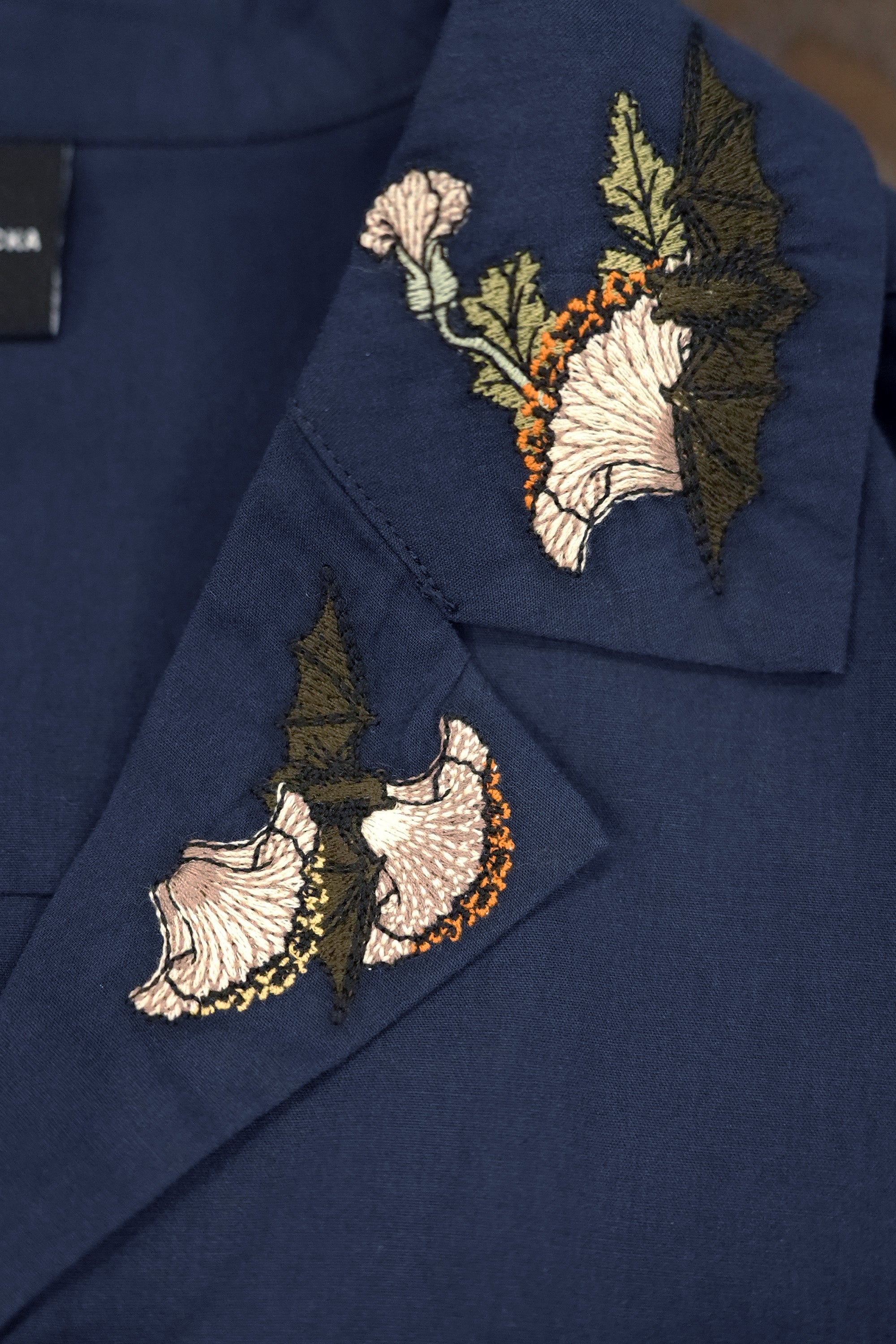 Close-up of embroidered collar detailing on navy cropped top, showcasing intricate floral embroidery and stitchwork