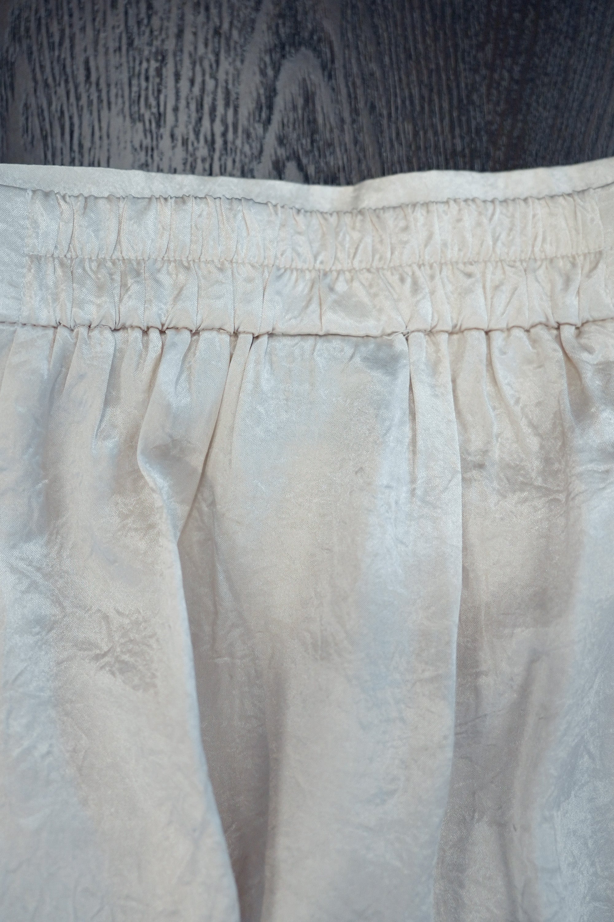 Close-up of back waistband showing elasticated construction for comfort with gathered detailing and structured pleats