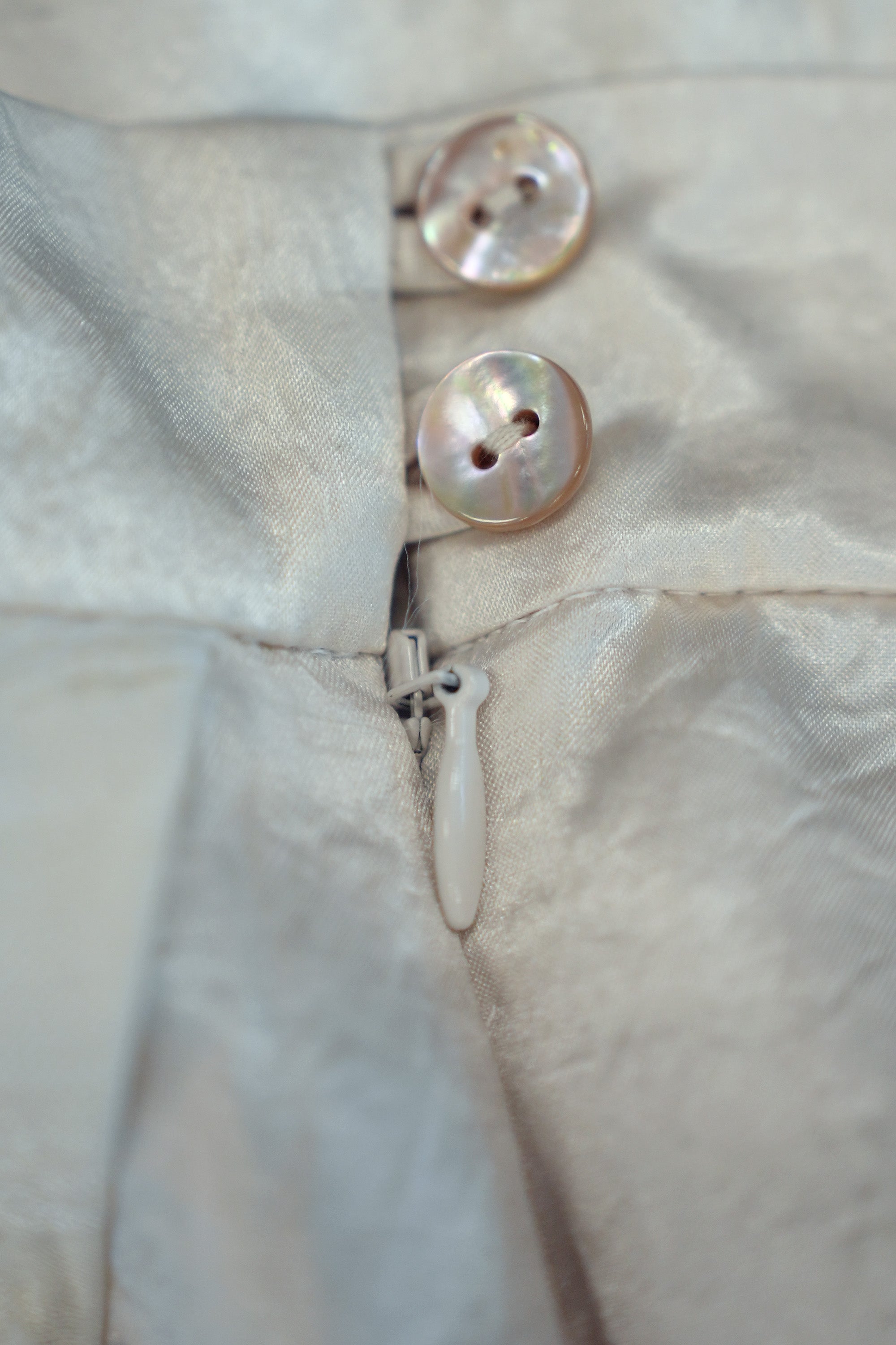 Close-up of skirt waistband featuring shell buttons and concealed zip closure with clean finishing