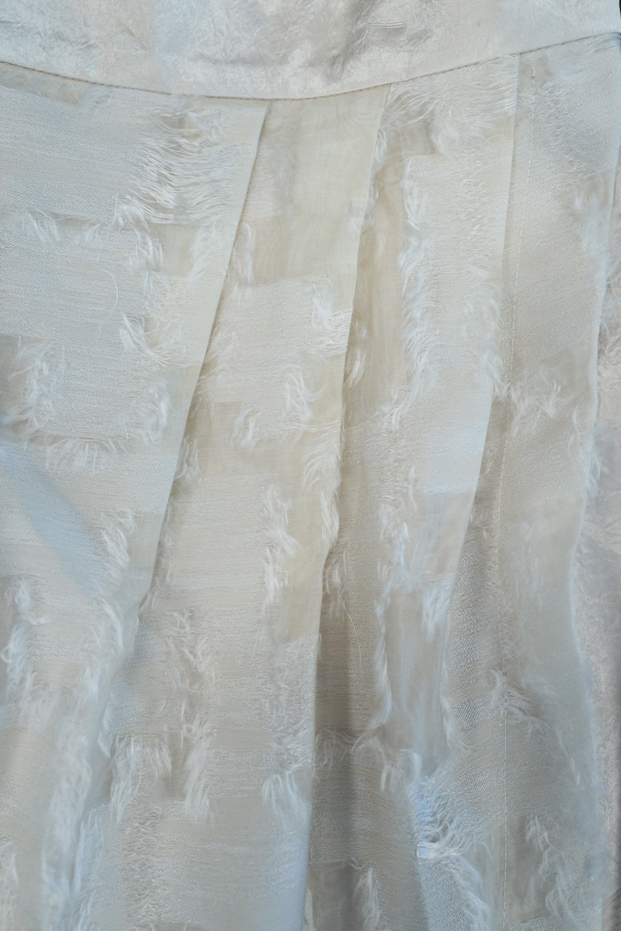 Close-up of faux wrap pencil skirt fabric showing textured jacquard surface with soft sheen and subtle tonal variation