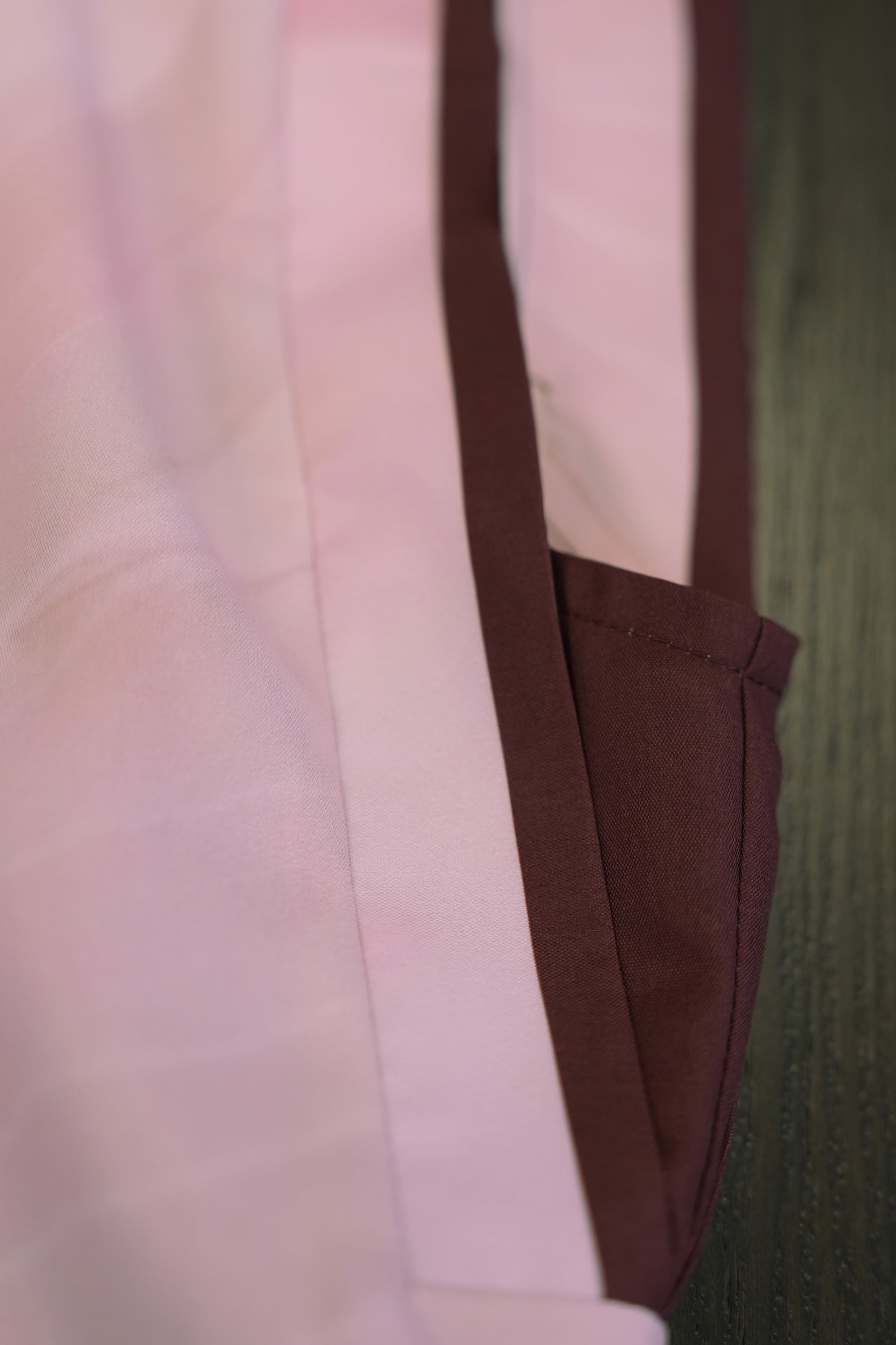 Close-up of blush pink top highlighting square sleeve construction with contrast burgundy trim, showcasing structured edges, clean stitching, and crisp, architectural sleeve shape