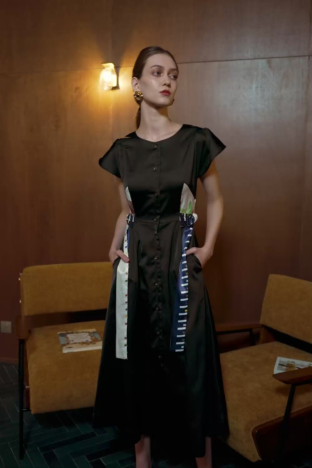 Model in Nymphaea Lotus Tulip Contour Dress — black silhouette with striped sashes and floral print panels in motion