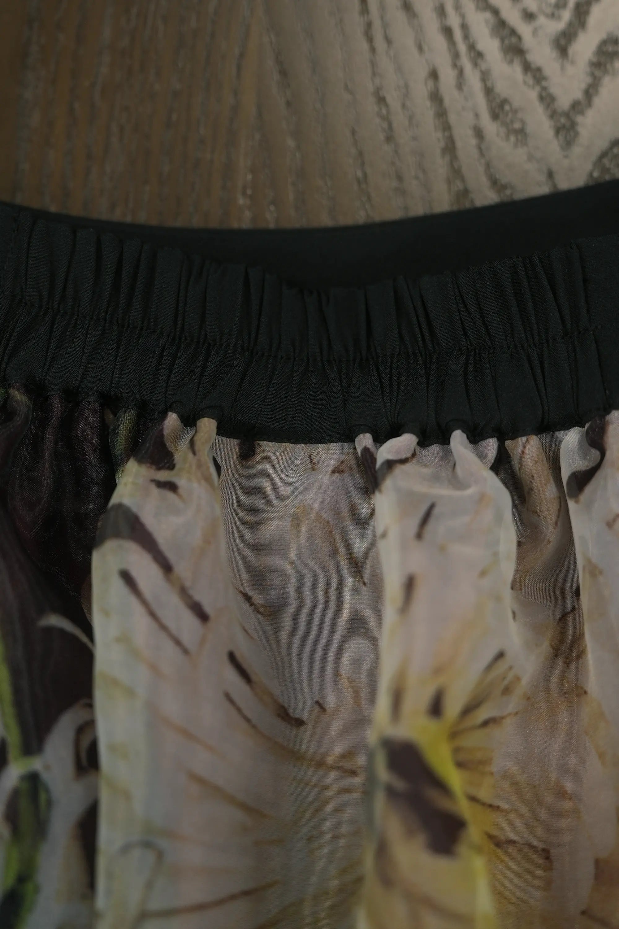 Close-up of skirt waistband with elasticised gathering, highlighting comfortable stretch fit, soft ruching, and the delicate drape of the sheer floral overlay beneath