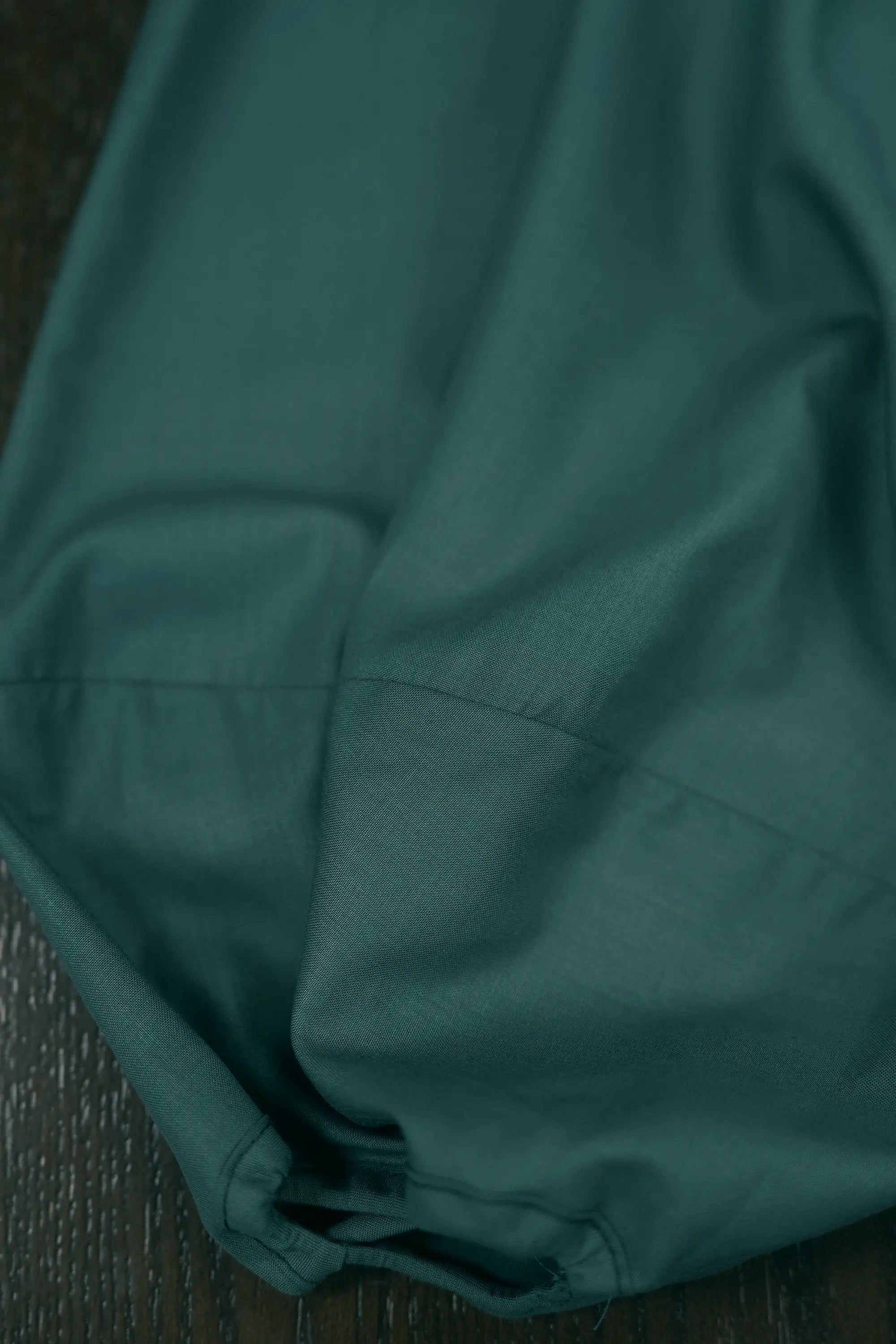 Close-up of deep green top sleeve detailing, highlighting softly gathered volume, clean seam lines, and smooth fabric drape for a relaxed yet structured silhouette