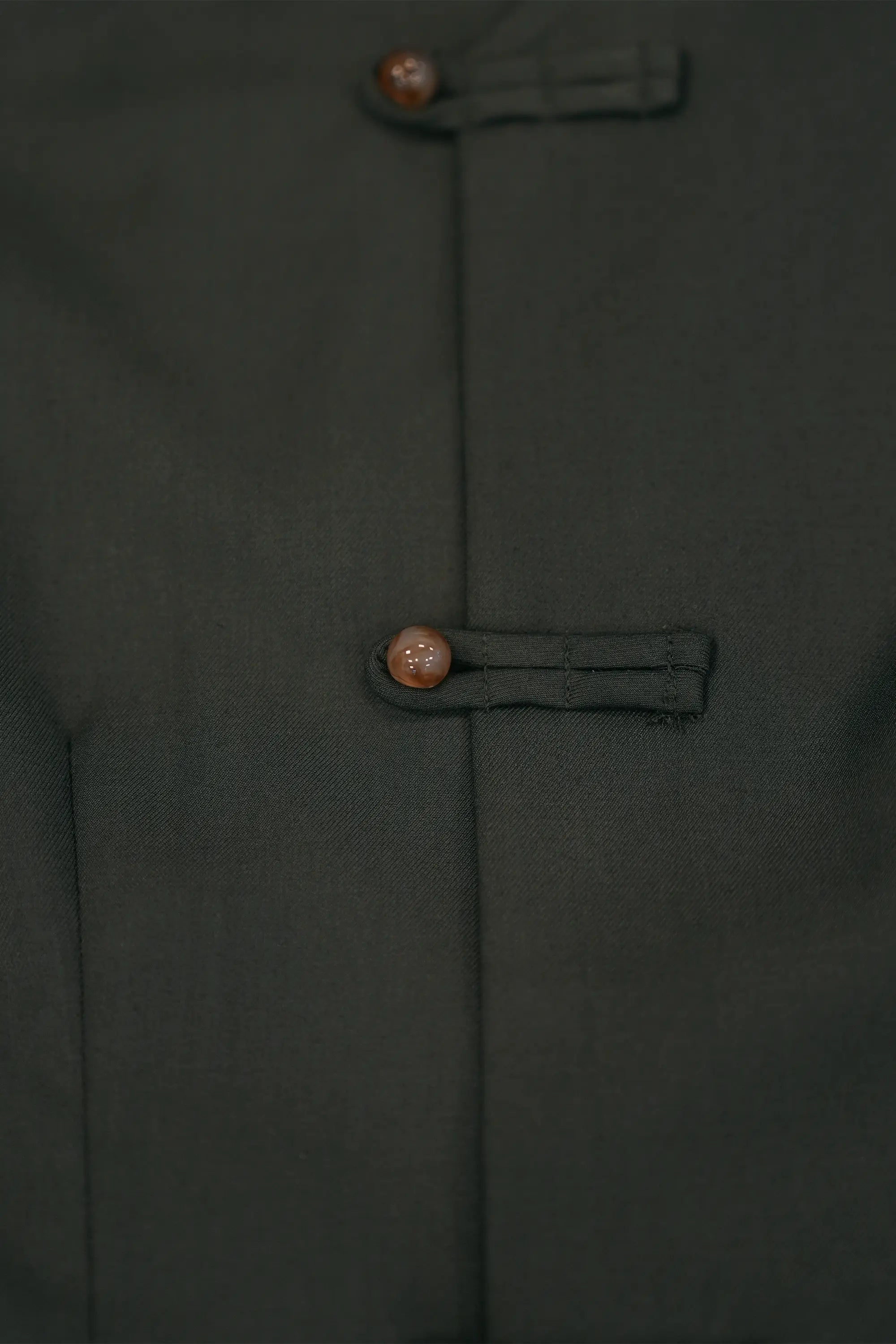 Close-up of deep green top featuring traditional pankou button closure, highlighting precise stitching, smooth fabric texture, and refined fastening detail