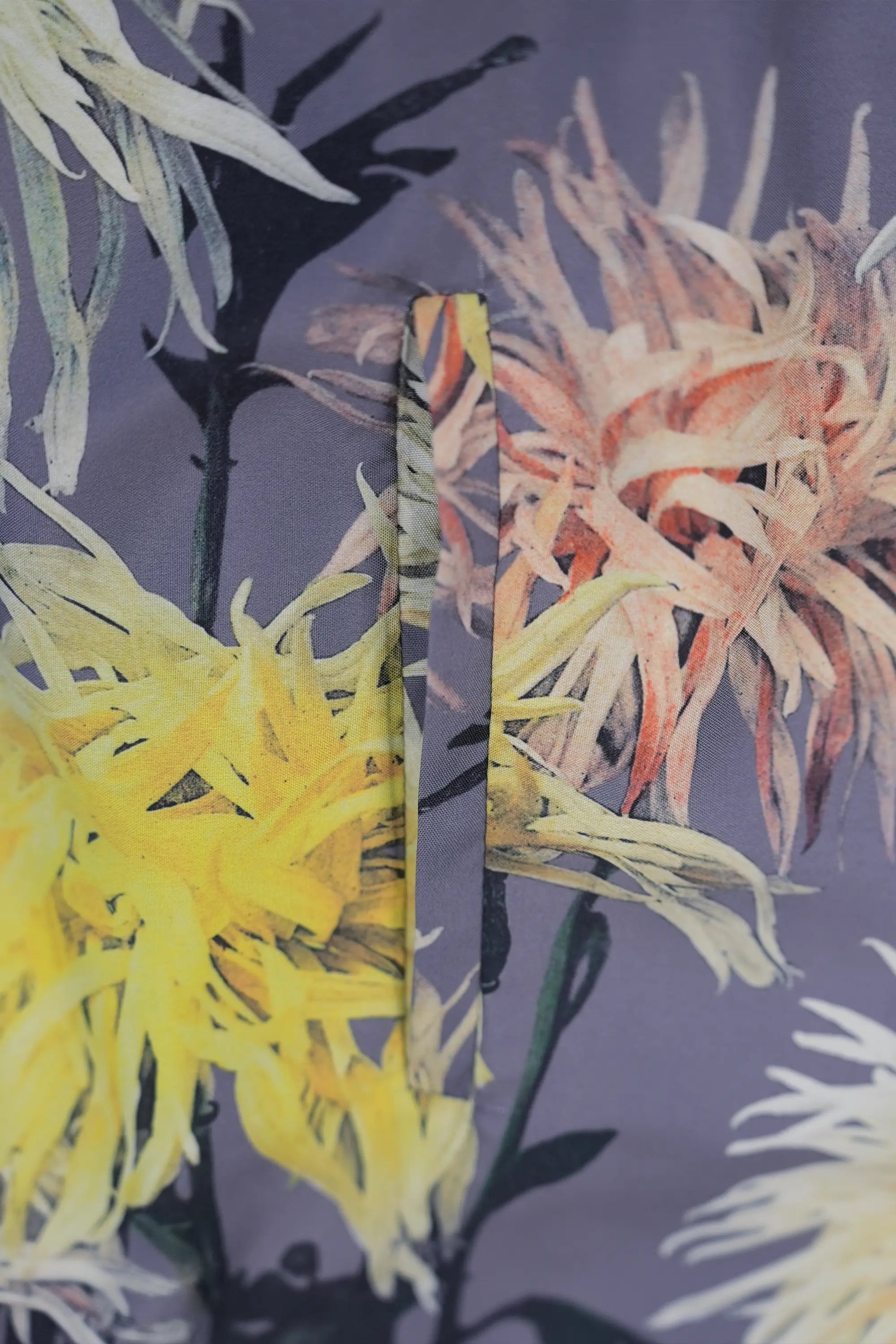 Close-up of floral printed fabric in muted grey base with yellow and coral chrysanthemum motifs