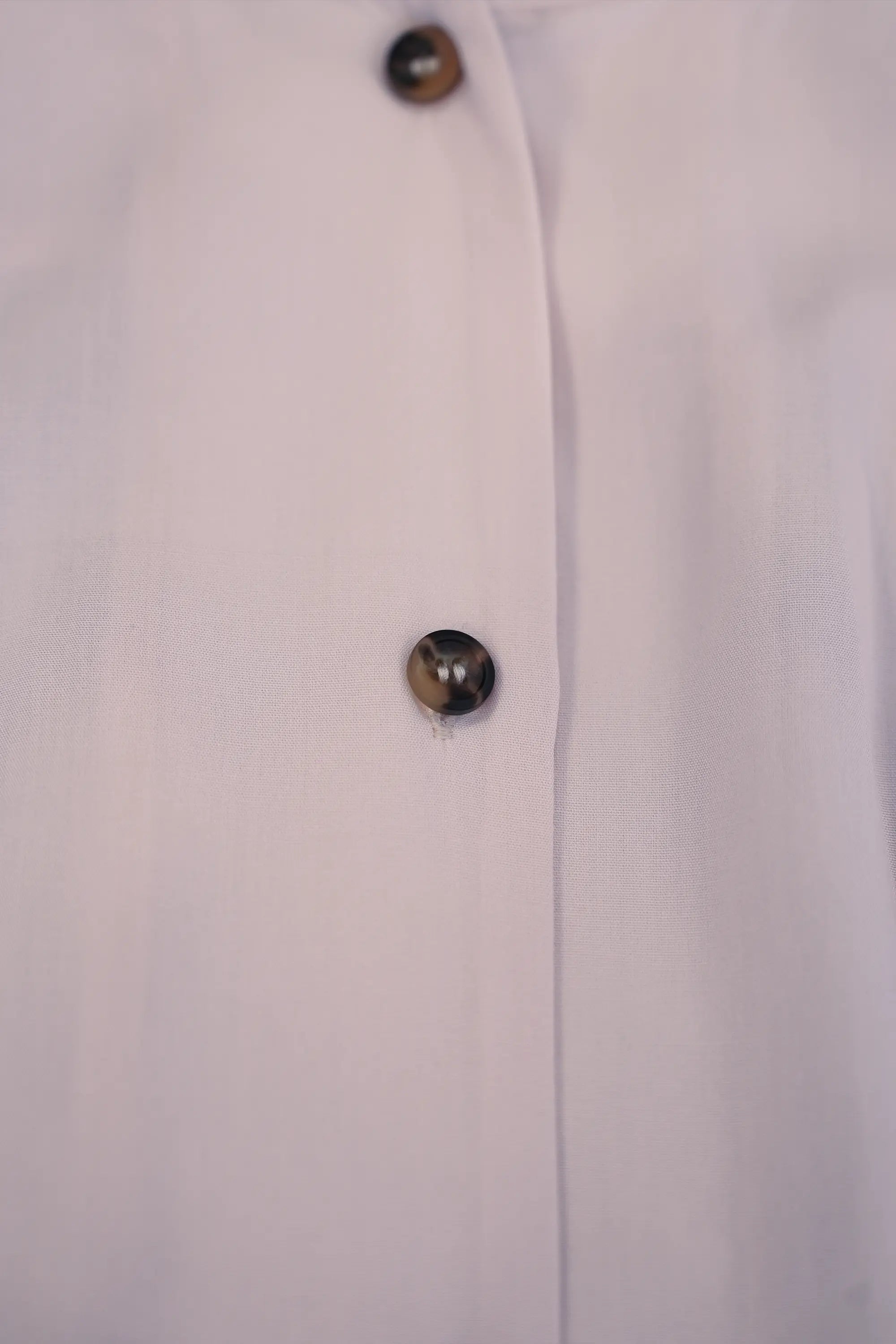 Close-up of blush pink blouse showing back pleat detail and clean seam construction