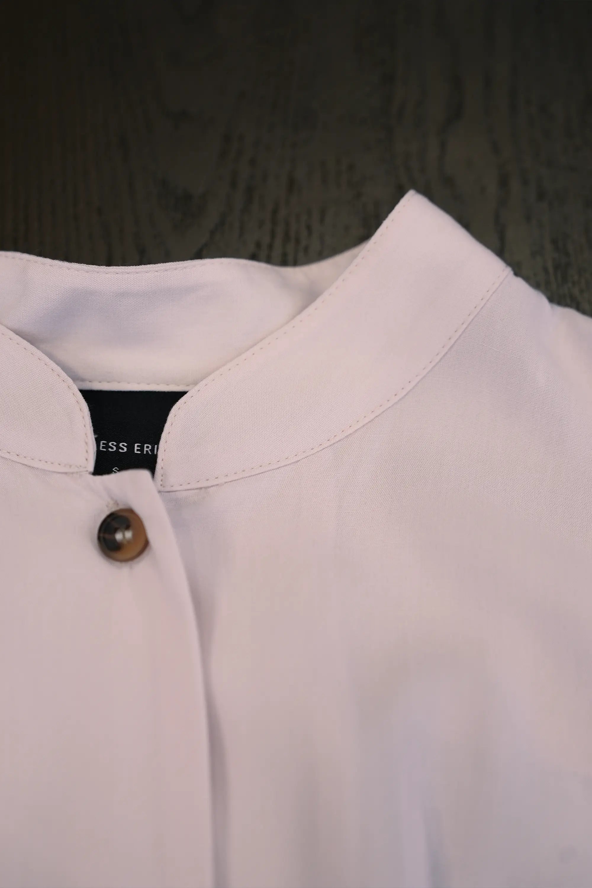Close-up of blush pink blouse with micro Chinese collar and clean stitched neckline detail

