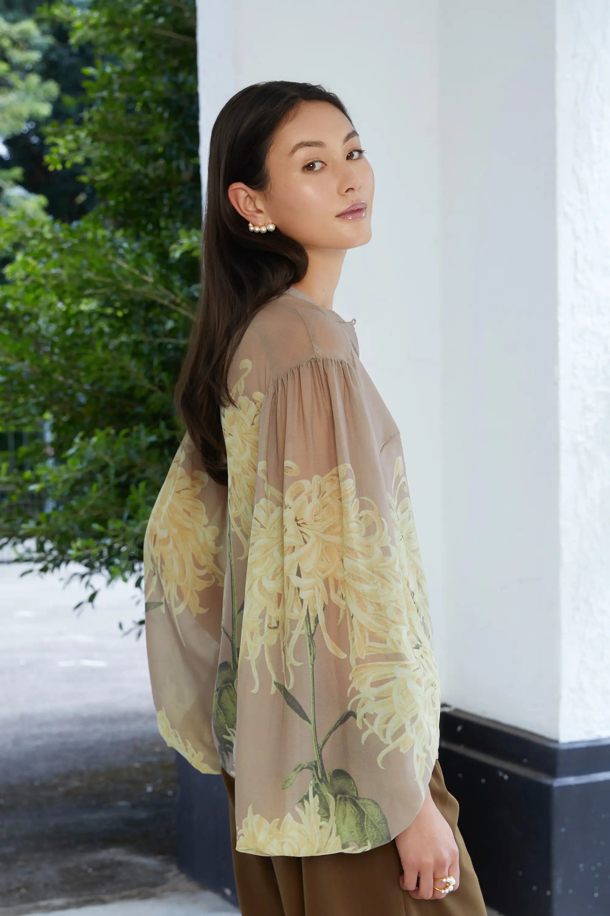 Woman wearing ABIDE sheer floral blouse with voluminous sleeves (side view)