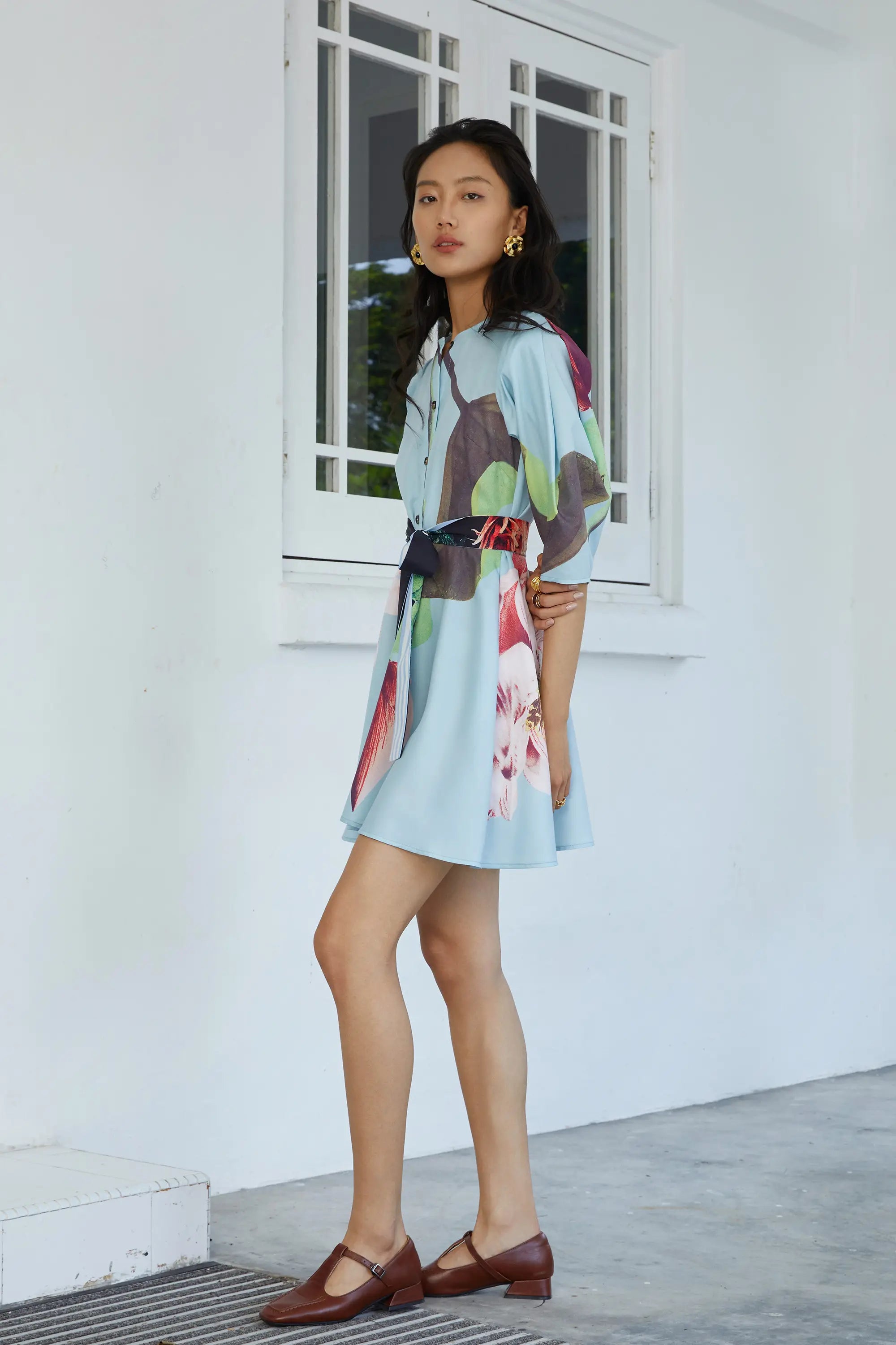Woman wearing ABIDE printed mini dress with waist sash and soft drape (side view)