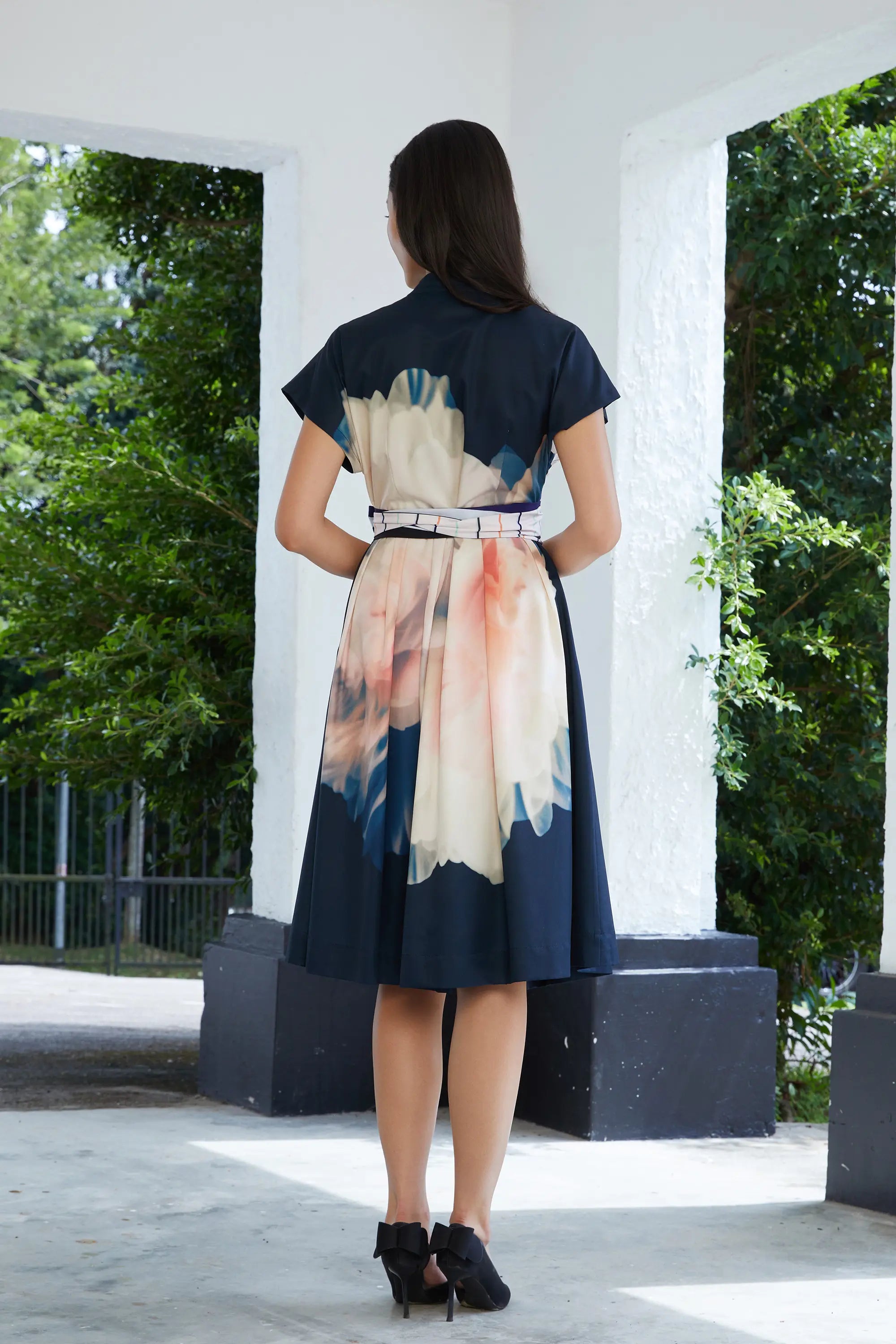 Woman wearing ABIDE placement print midi dress with sash belt and soft drape (back view)