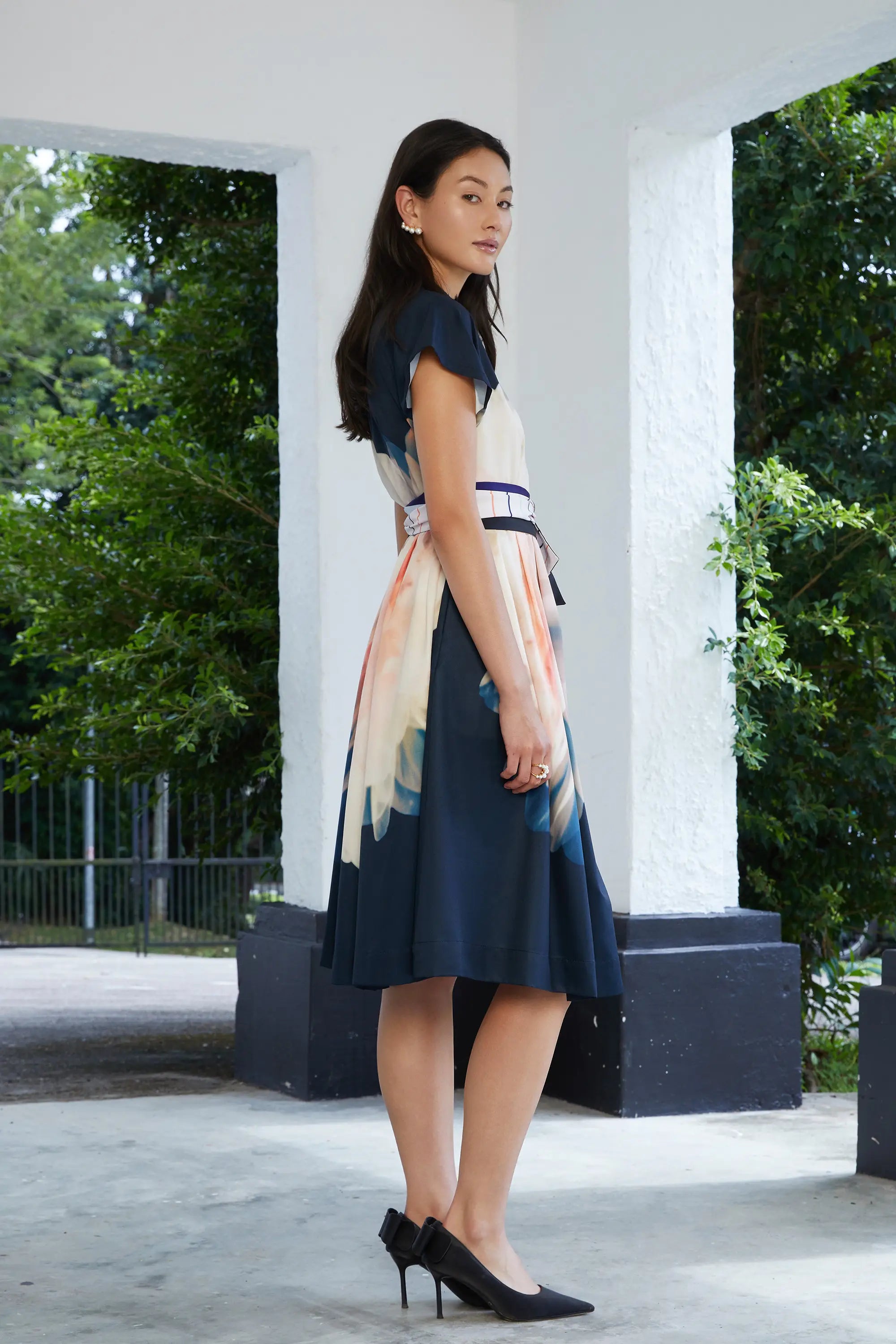 Woman wearing ABIDE placement print dress with sash belt and flutter sleeves (side view)