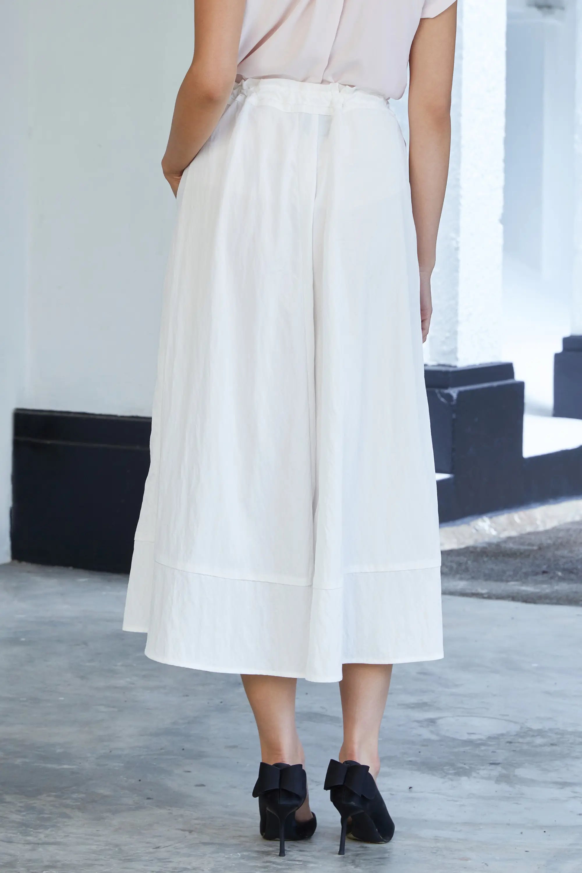 Woman wearing ABIDE white lace wide-leg cropped pants with drawstring waist and relaxed fit (back view)