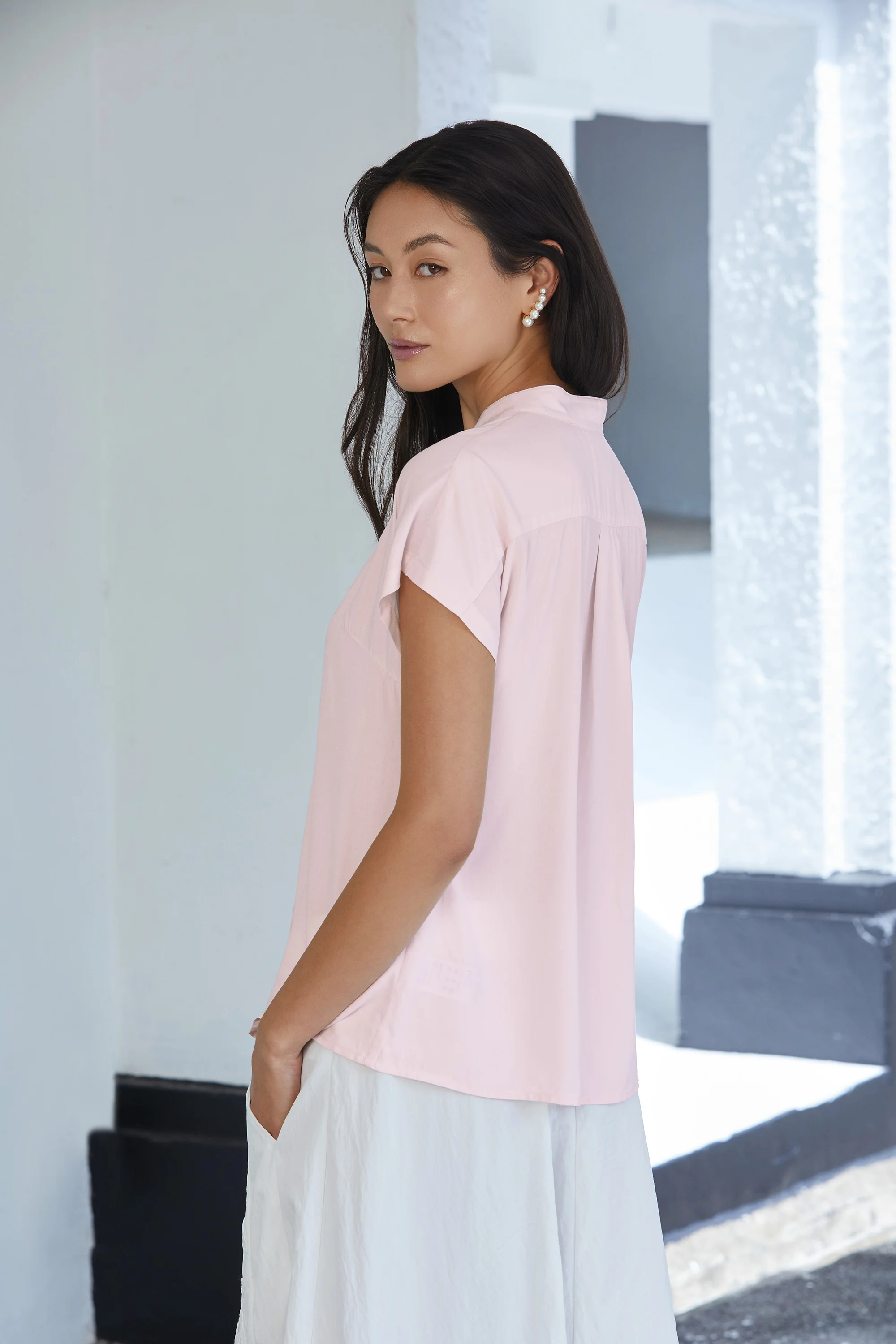 Side view of blush pink blouse with clean drape, short sleeves and relaxed silhouette