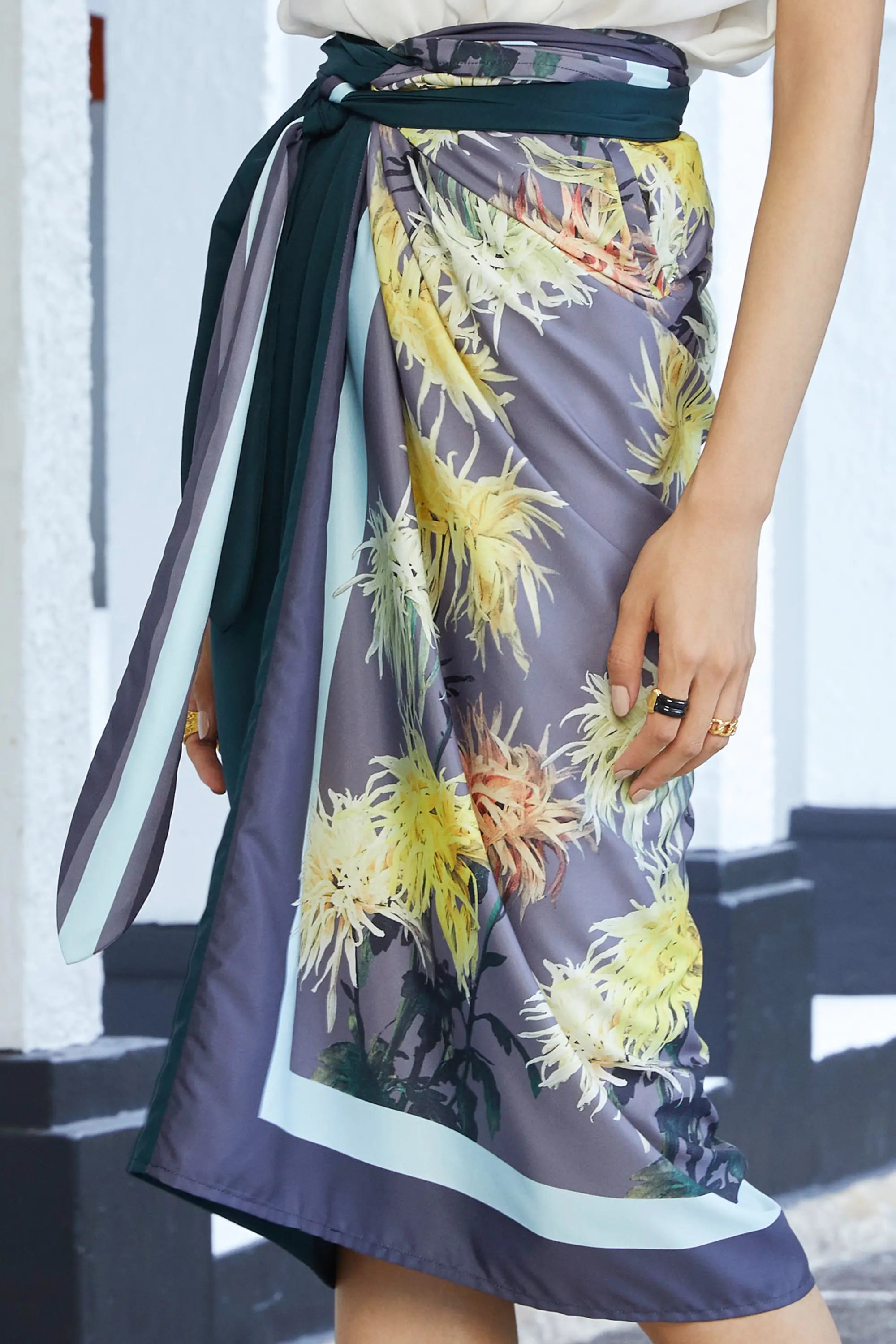 Close-up of wrap skirt with floral print, contrasting sash tie, and asymmetrical draped front
