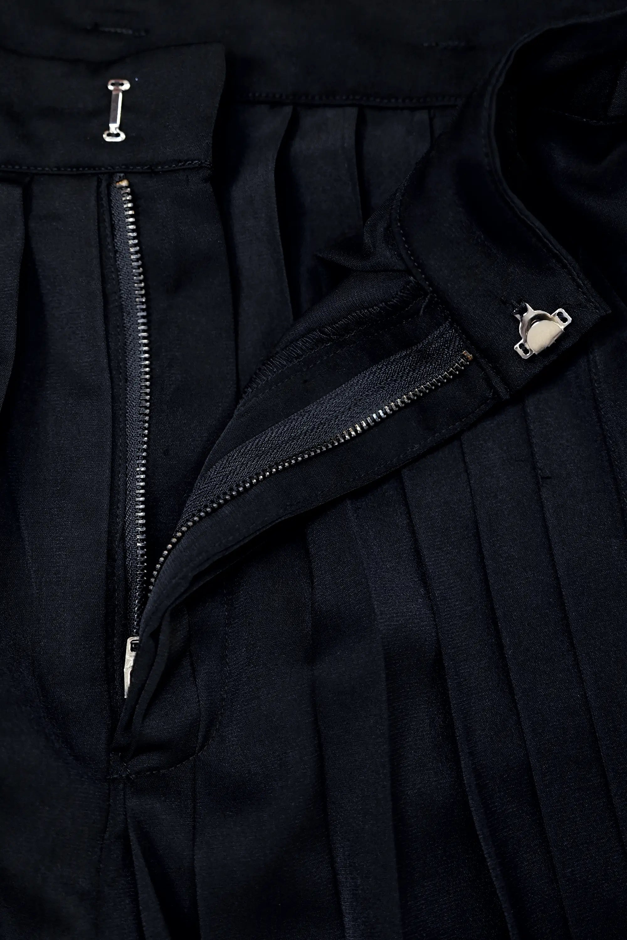Close-up of zip closure on Arrayed black pleated skirt trousers
