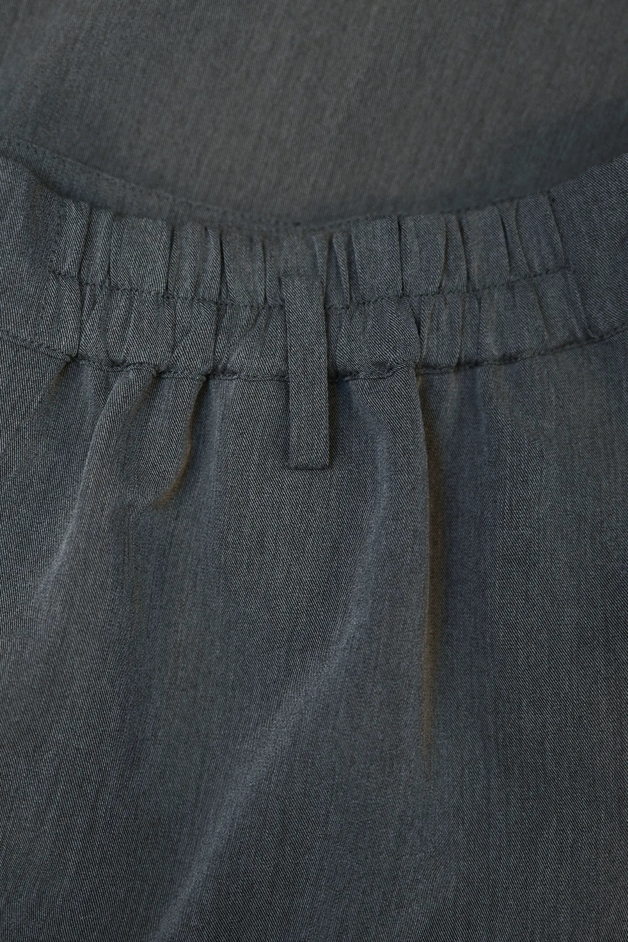 Close-up of elasticated back waist on Arrayed dark grey wrap trousers