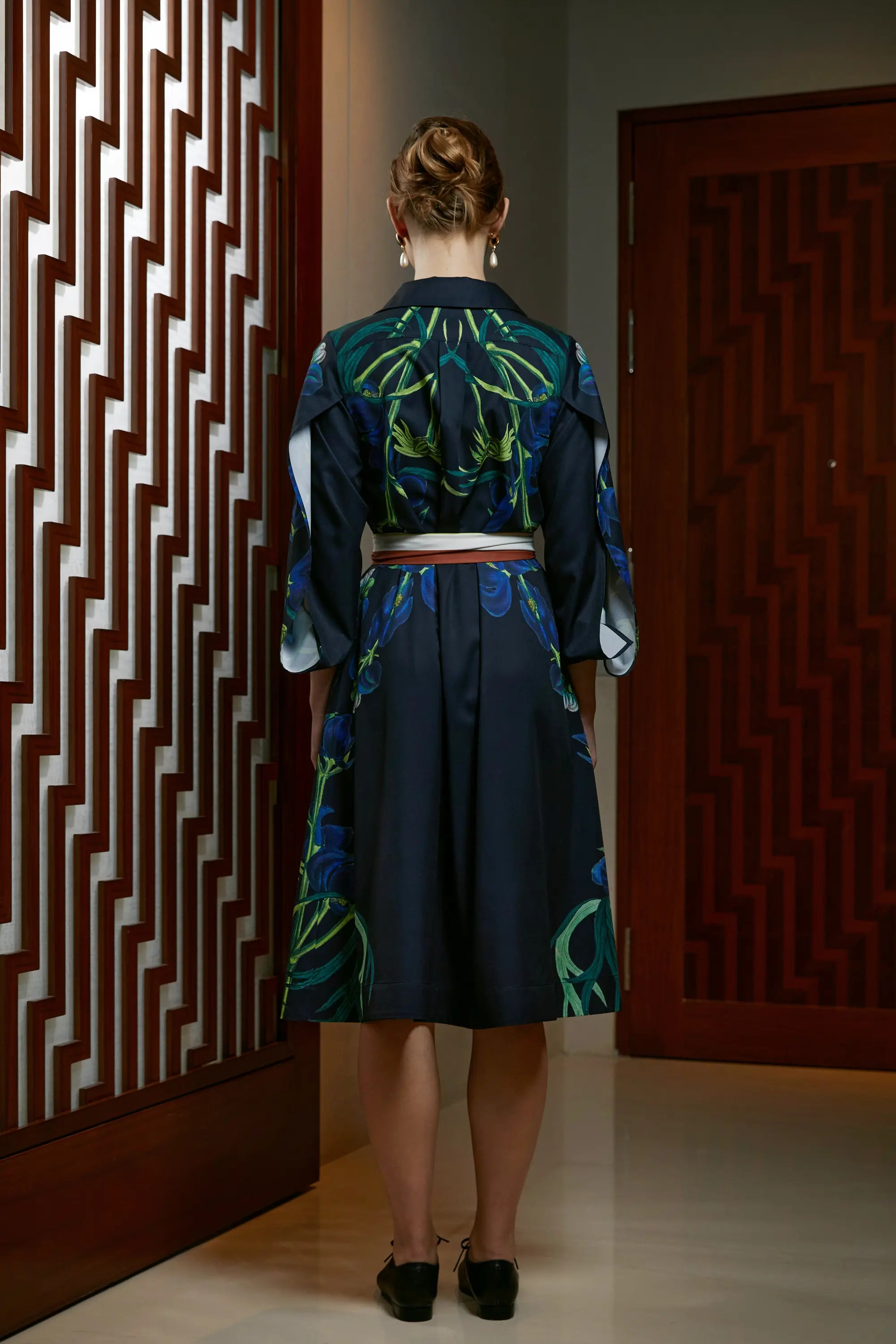 Woman wearing Arrayed Monk's Hood print shirt dress in black, back view