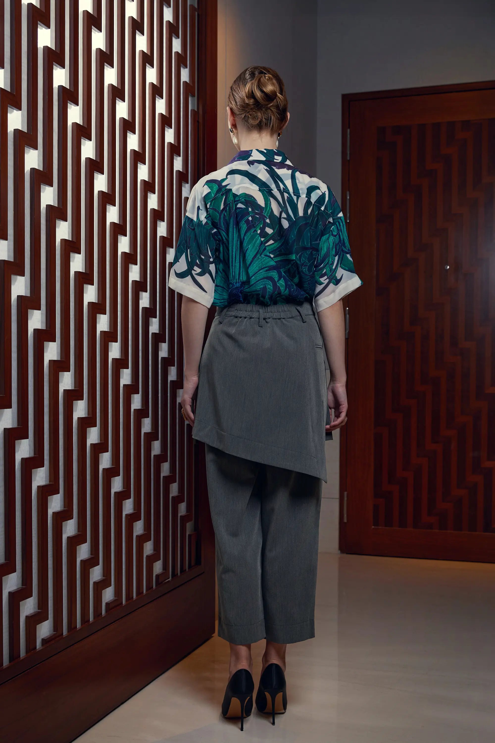 Woman wearing Arrayed Chrysanthemum Cuban shirt with dark grey wrap trousers, back view