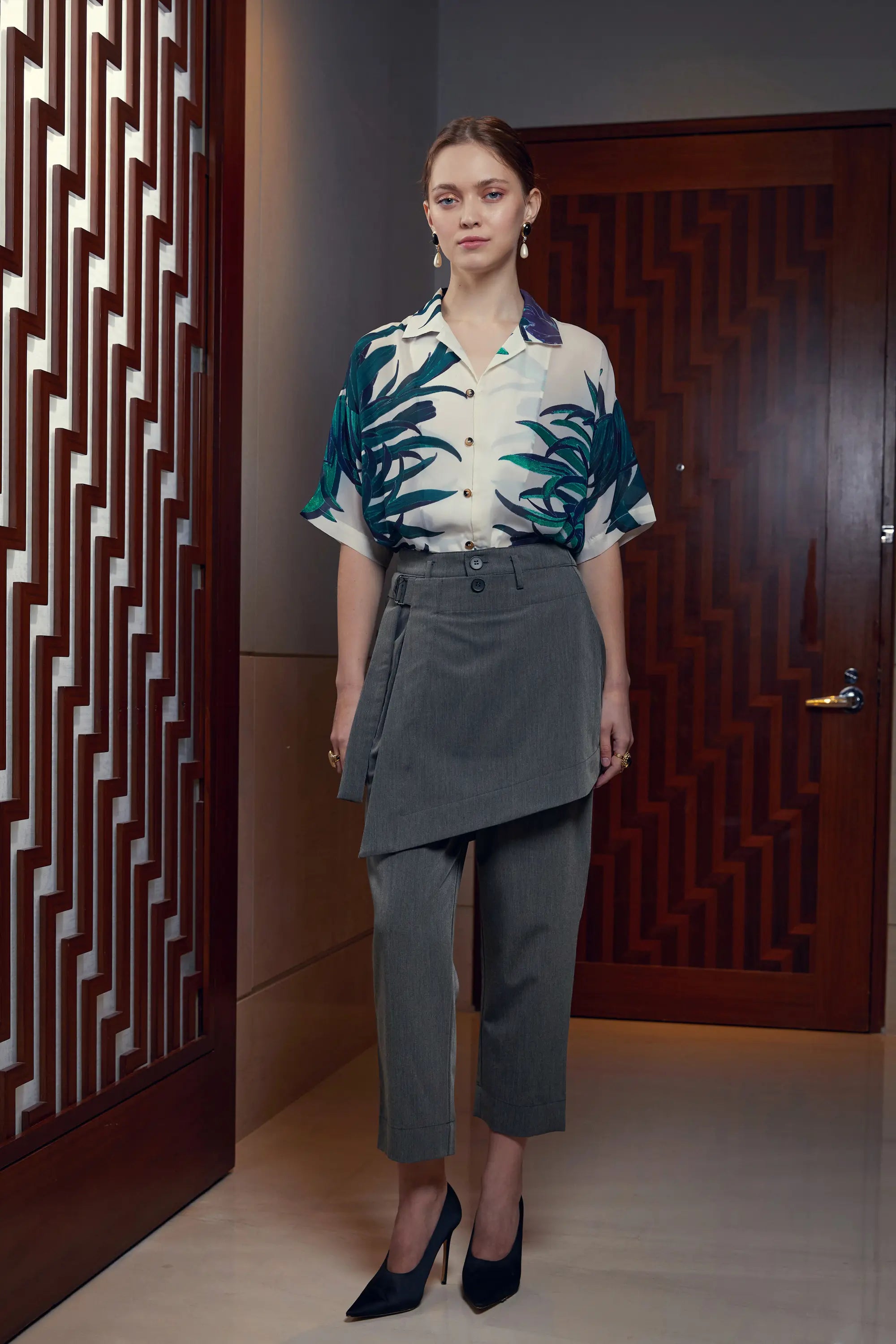 Woman wearing Arrayed Chrysanthemum Cuban shirt with dark grey wrap trousers, front view