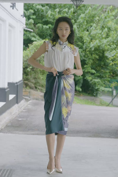 Close-up video of white blouse with printed collar paired with wrap skirt, highlighting contrast floral panel, sash tie, and draped front