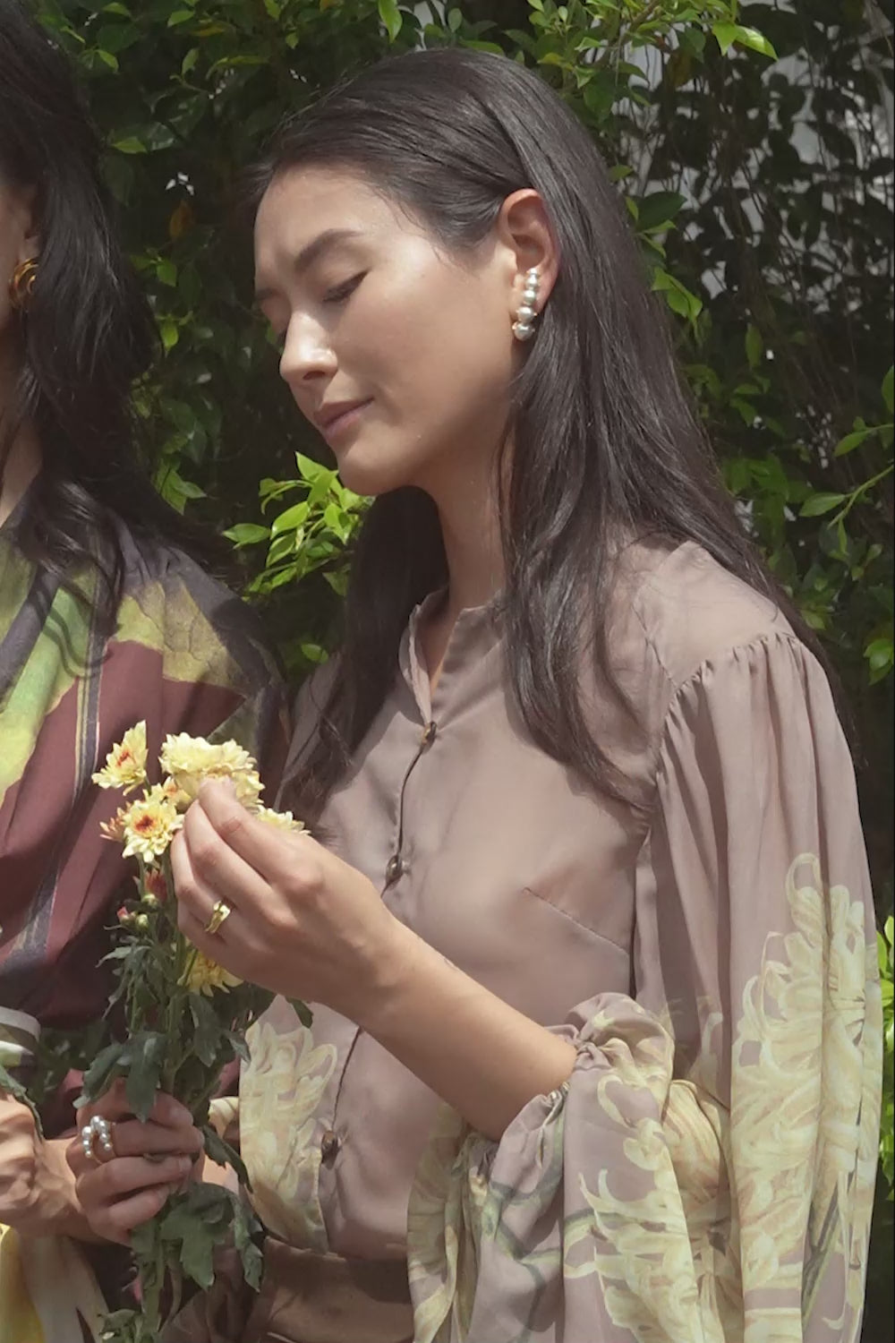 Woman in ABIDE floral blouse with voluminous sleeves and brown wide-leg pants outdoors