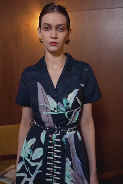 Model in Cymbidium Orchid panel dress with shawl collar — navy silhouette with floral print and striped waist sash